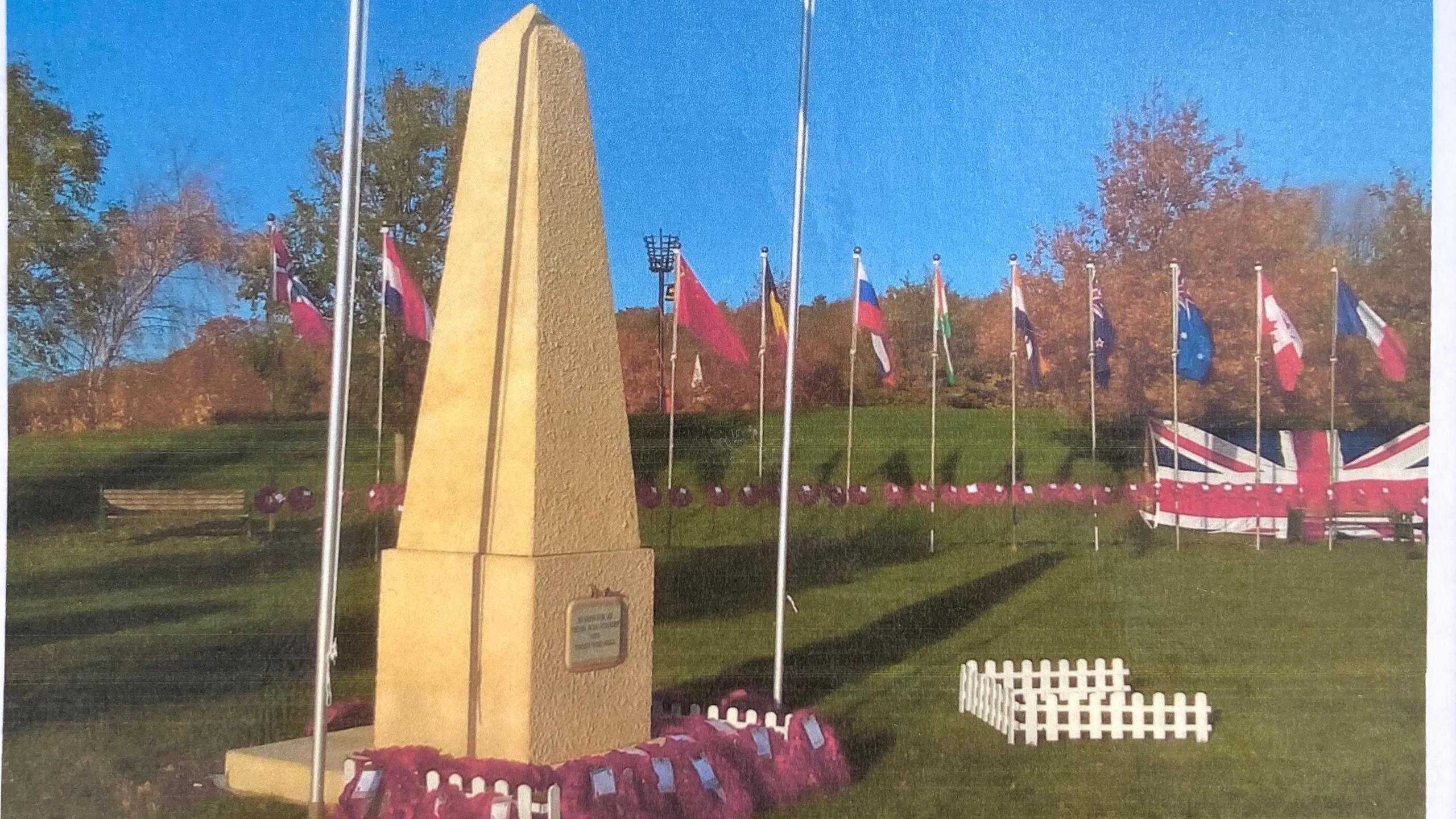 The temporary Cenotaph in Long Ashton with poppies at its base and flags in the background