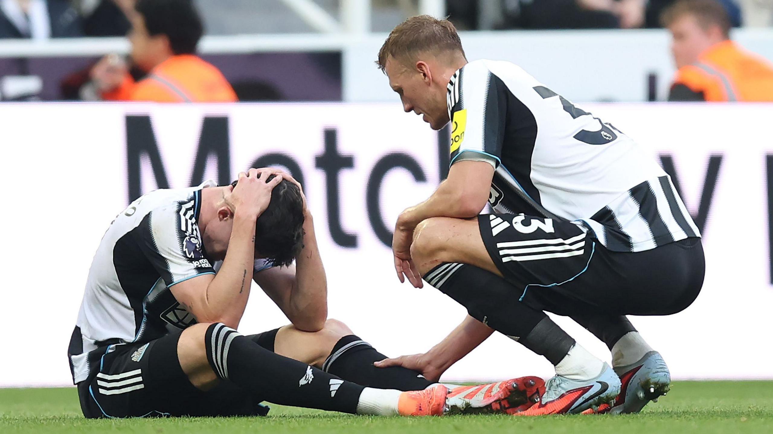Newcastle's Tino Livramento sits with his hands on his head after suffering an injury