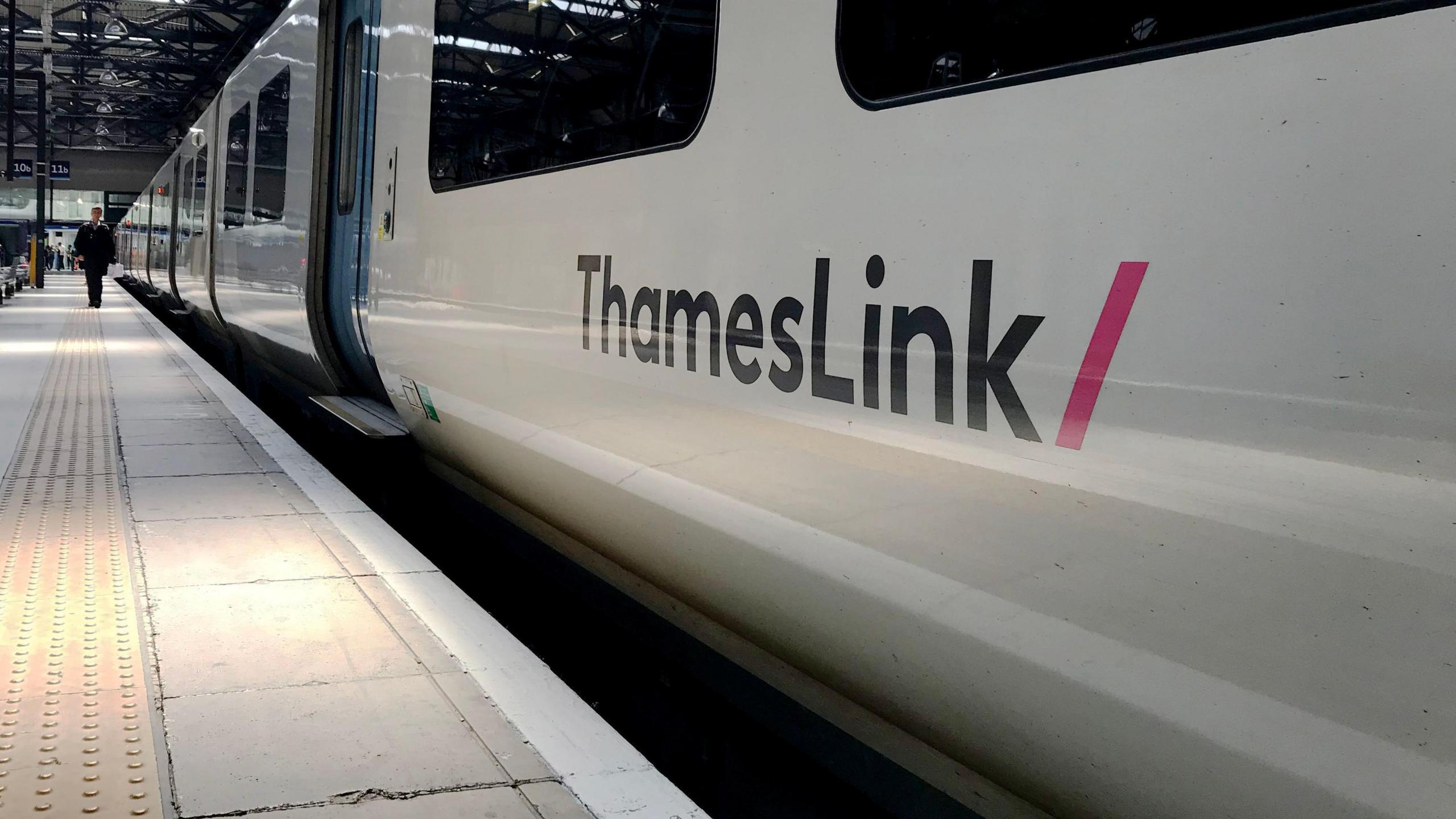 The side of a white ThamesLink train at a platform Kings Cross station in London