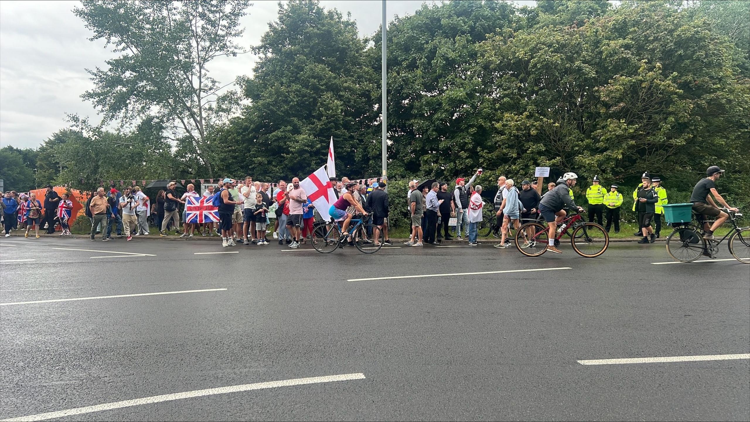 A large group of people holding the union jack and the St George 's flag. There are police officers at the scene.