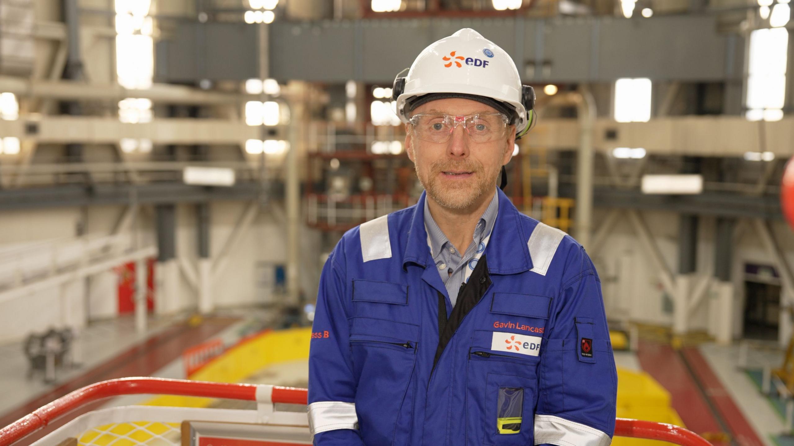 Gavin Lancaster - a man in a blue work suit with a white hard hat 