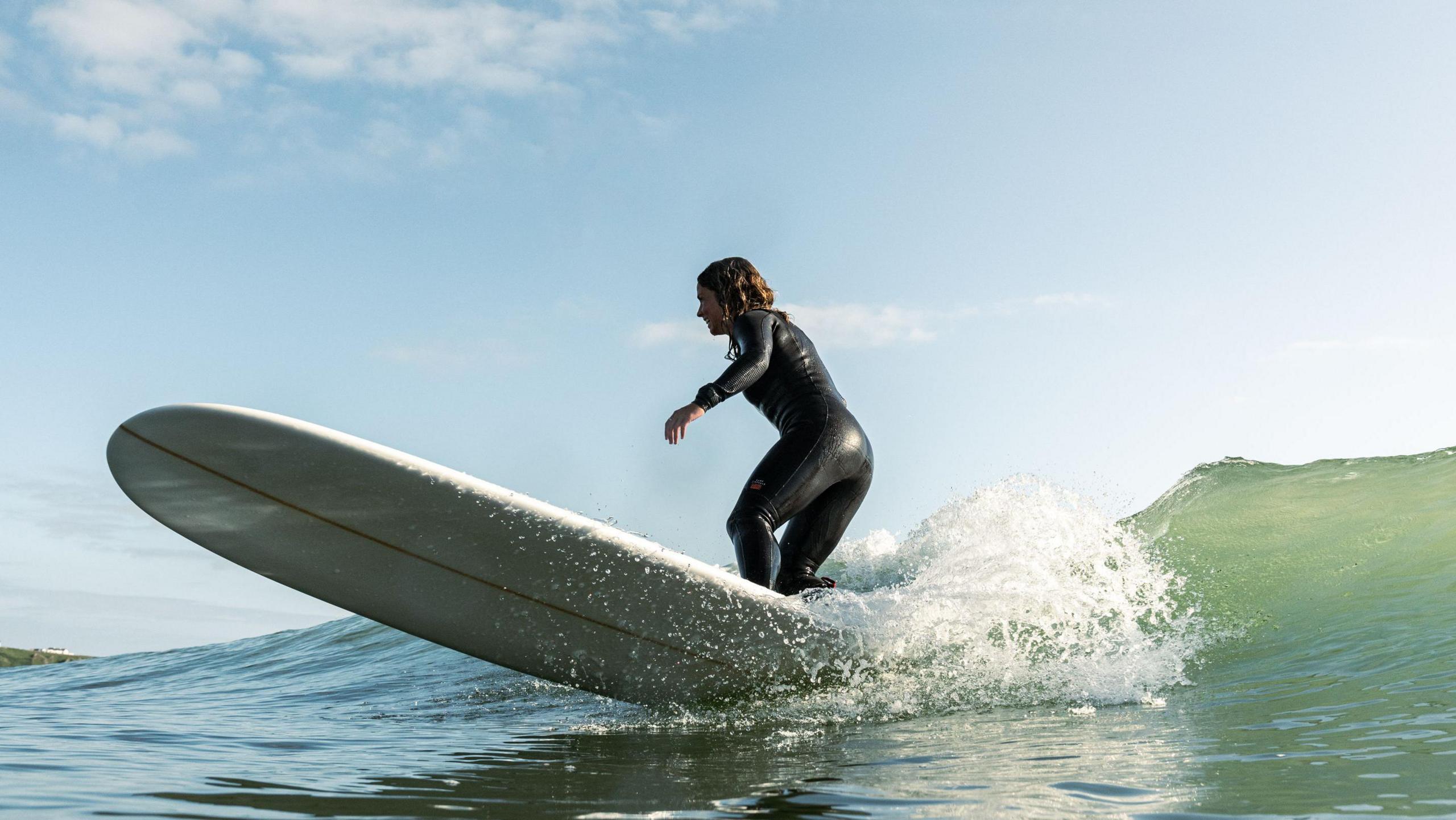 Steph Lowe surfing a longboard on an unbroken wave. 