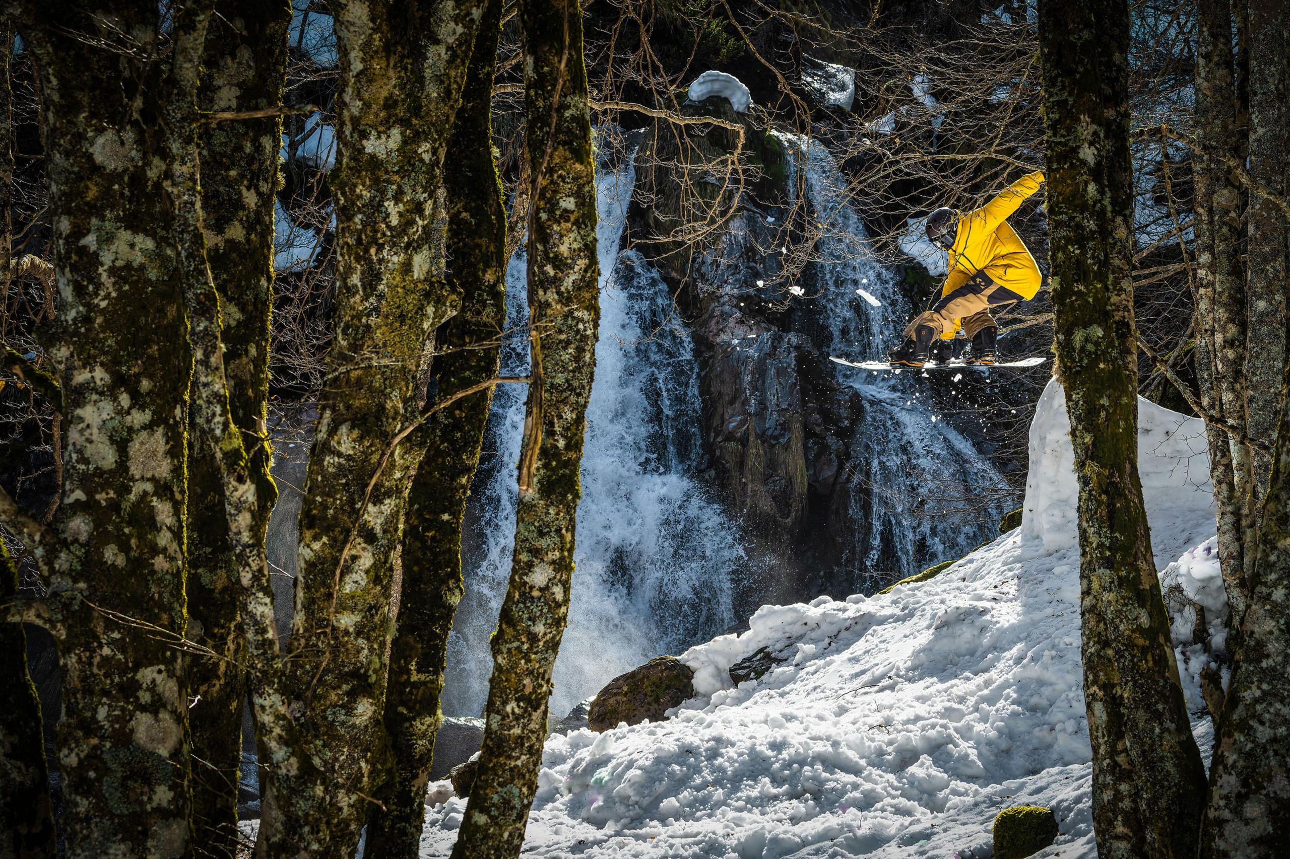 The Espelunguere waterfall providing a beautiful background for the snowboarder performing tricks in the foreground