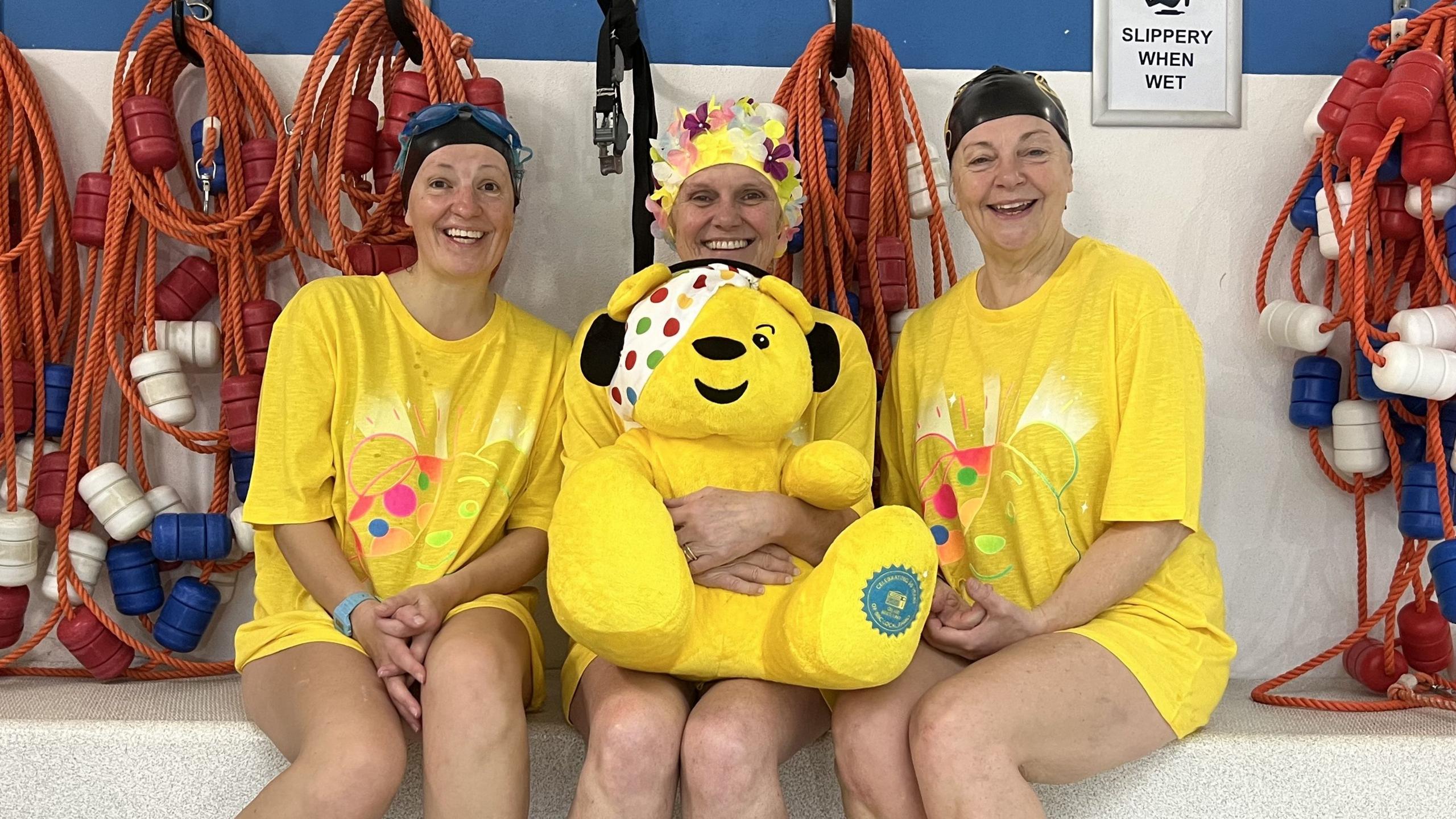 BBC Radio Cornwall's Hannah Stacey, Julie Skentelbery, and Daphne Skinnard sat together holding a Pudsey plush toy