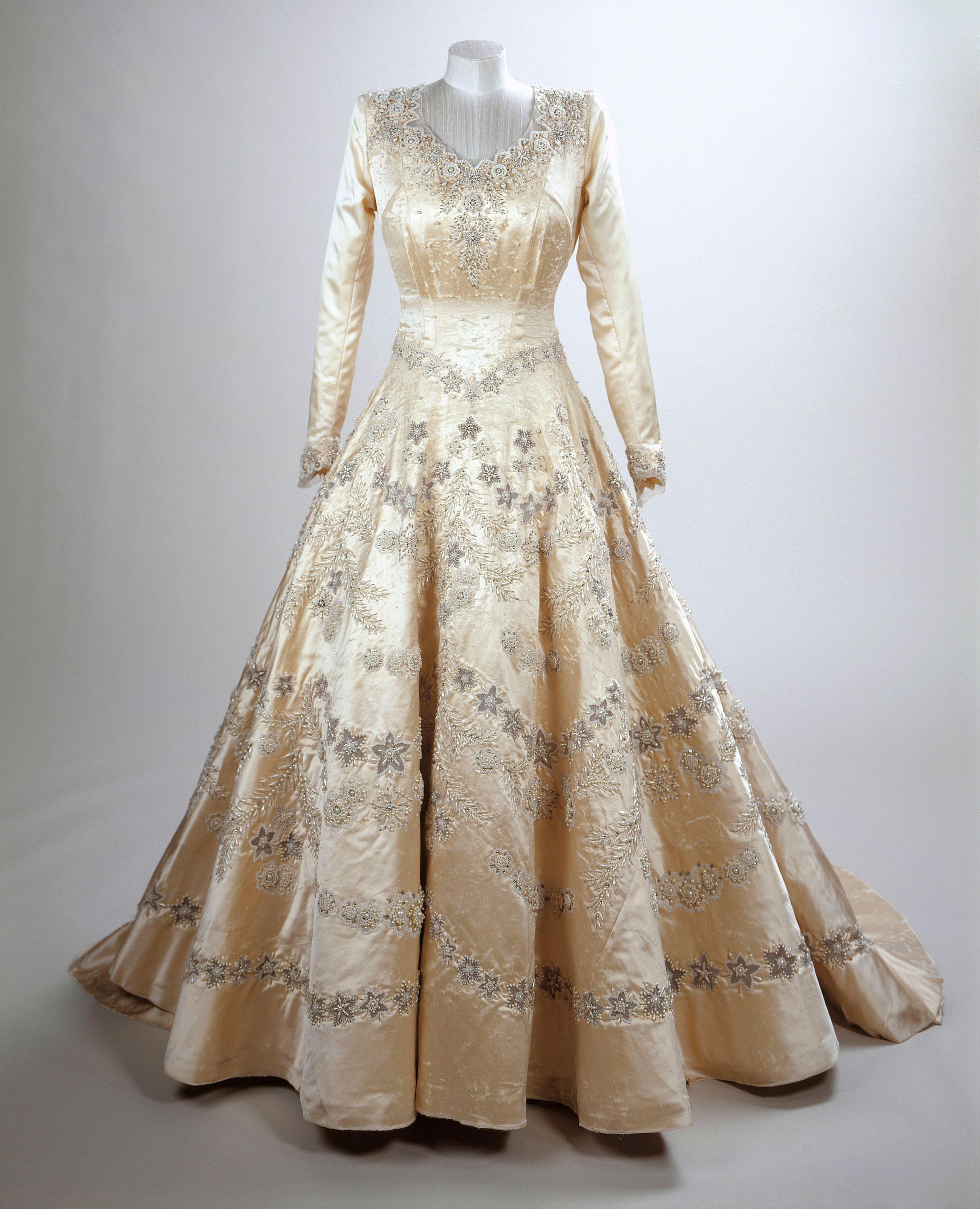 a long sleeved floor length dress embroidered with lots of flowers on a mannequin