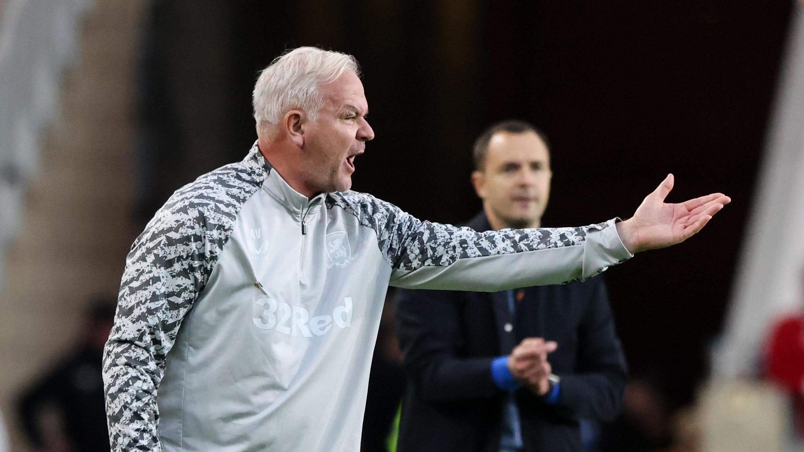 Adi Viveash pointing with his left hand towards Middlesbrough players with Birmingham head coach Chris Davies in the background 