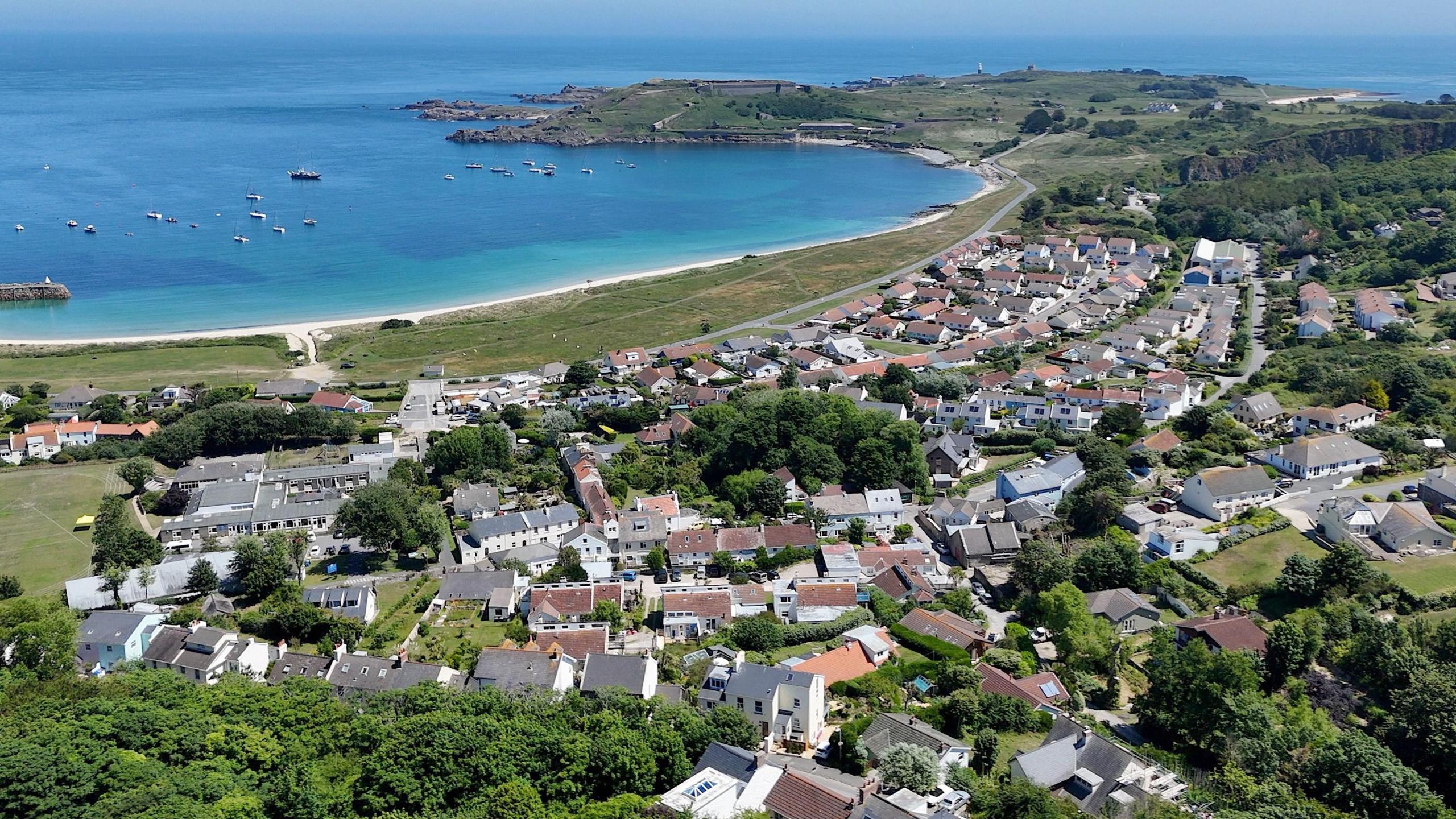 An aerial view of homes in Alderney and the bay of Newtown. Blue seas.