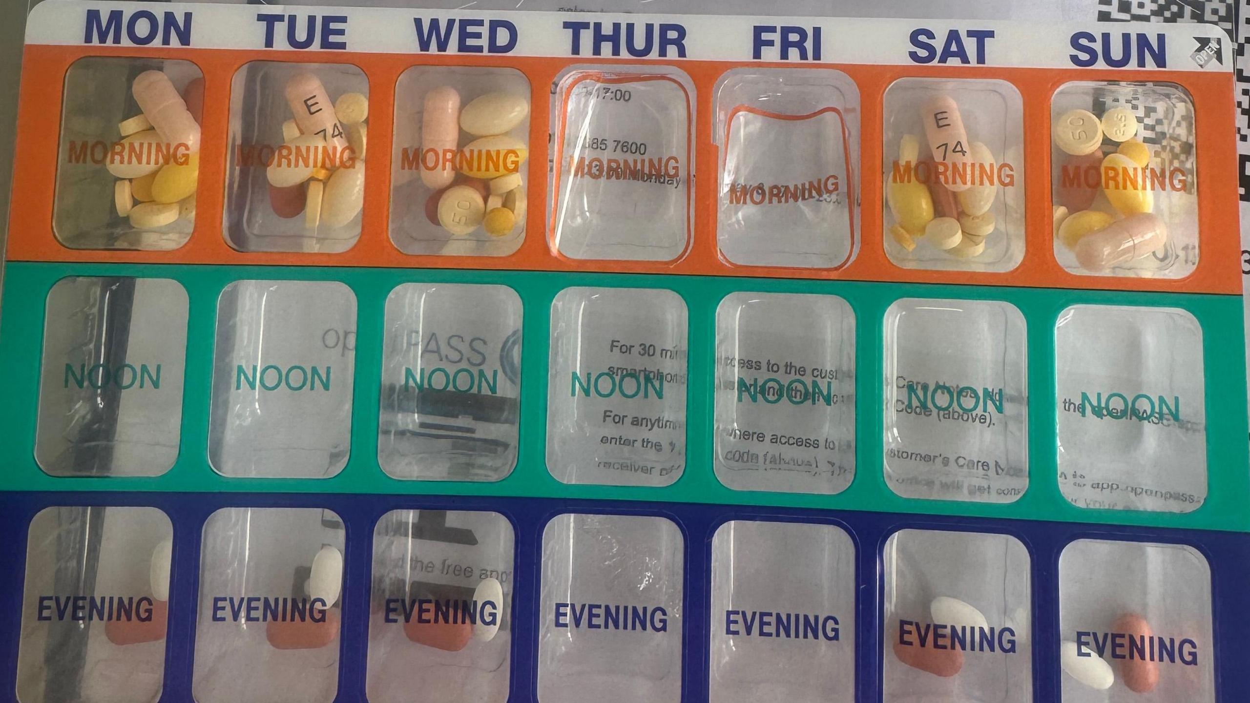 A blister pack containing tablets named Monday to Sunday and is labelled Morning , Noon and Evening. Colour coded Orange for morning, green for noon and blue for evening medication.