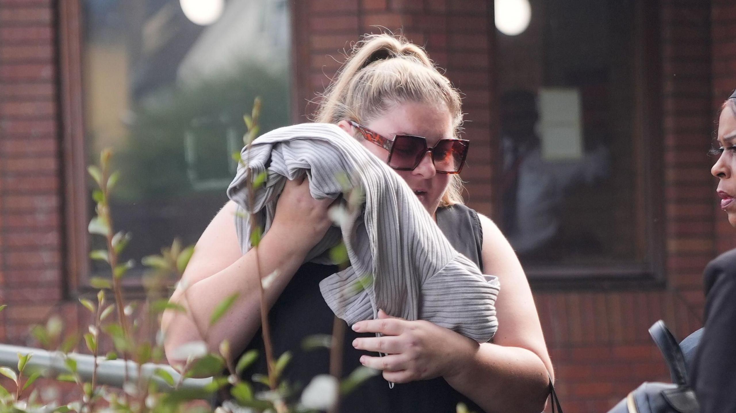 Hayley Jones leaves Wimbledon Magistrates' Court with a jumper held up to her face