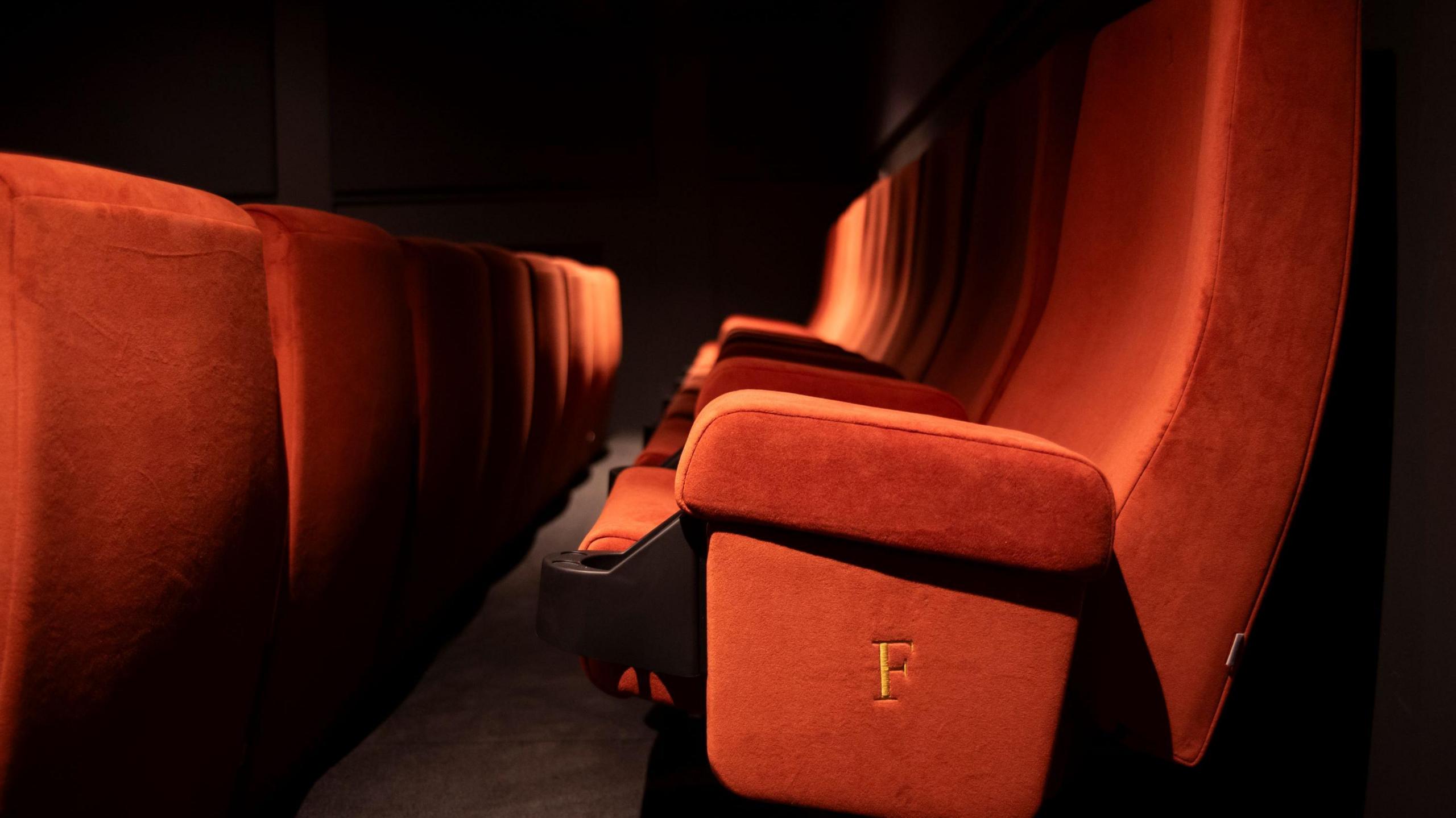 Deep red cinema seating in rows, in close-up.