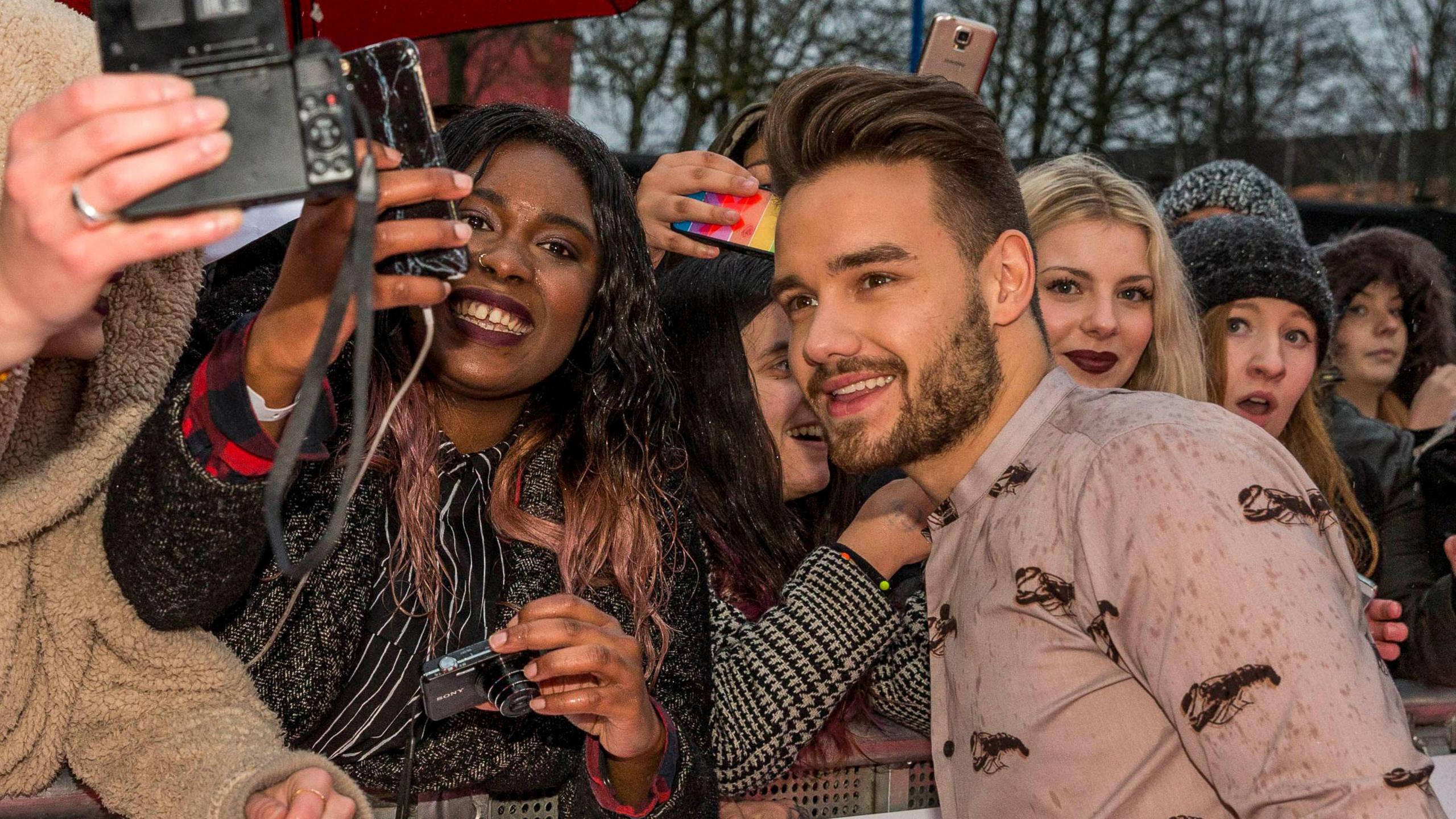 A man is taking pictures with fans at an awards show