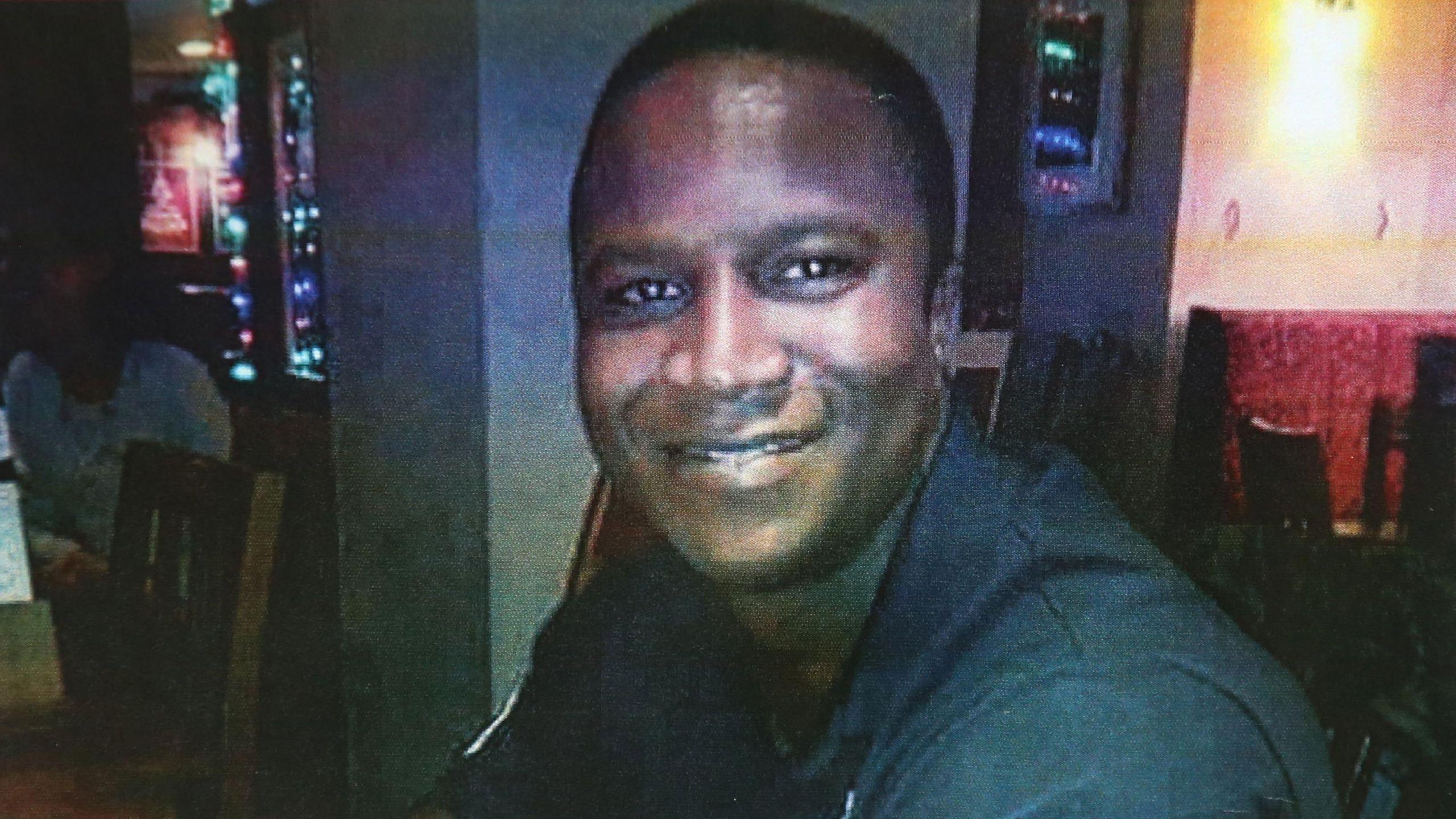 Sheku Bayoh photographed in a pub or restaurant setting smiling at the camera