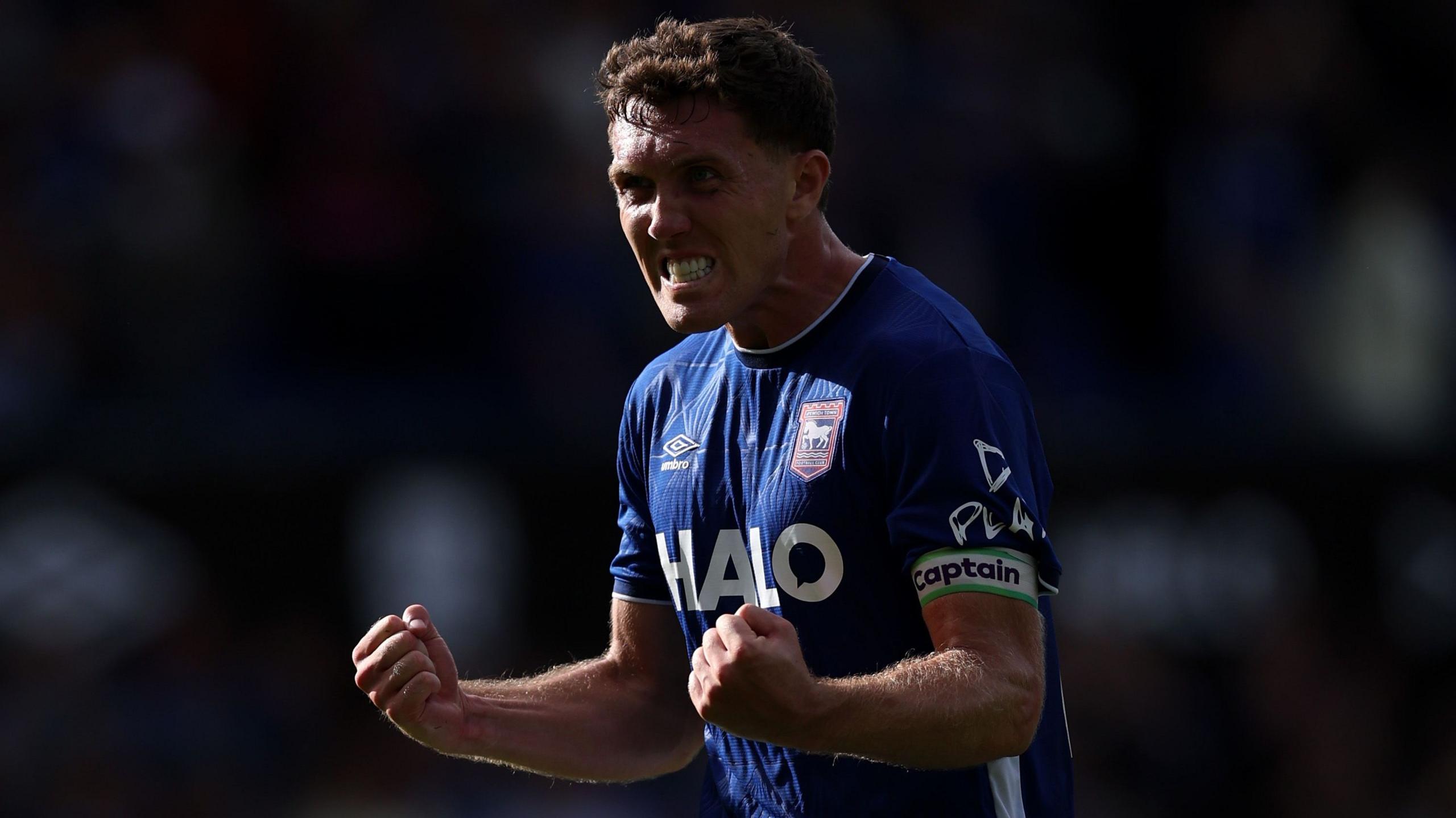 Dara O'Shea celebrates with clenched fists wearing a blue Ipswich Town kit