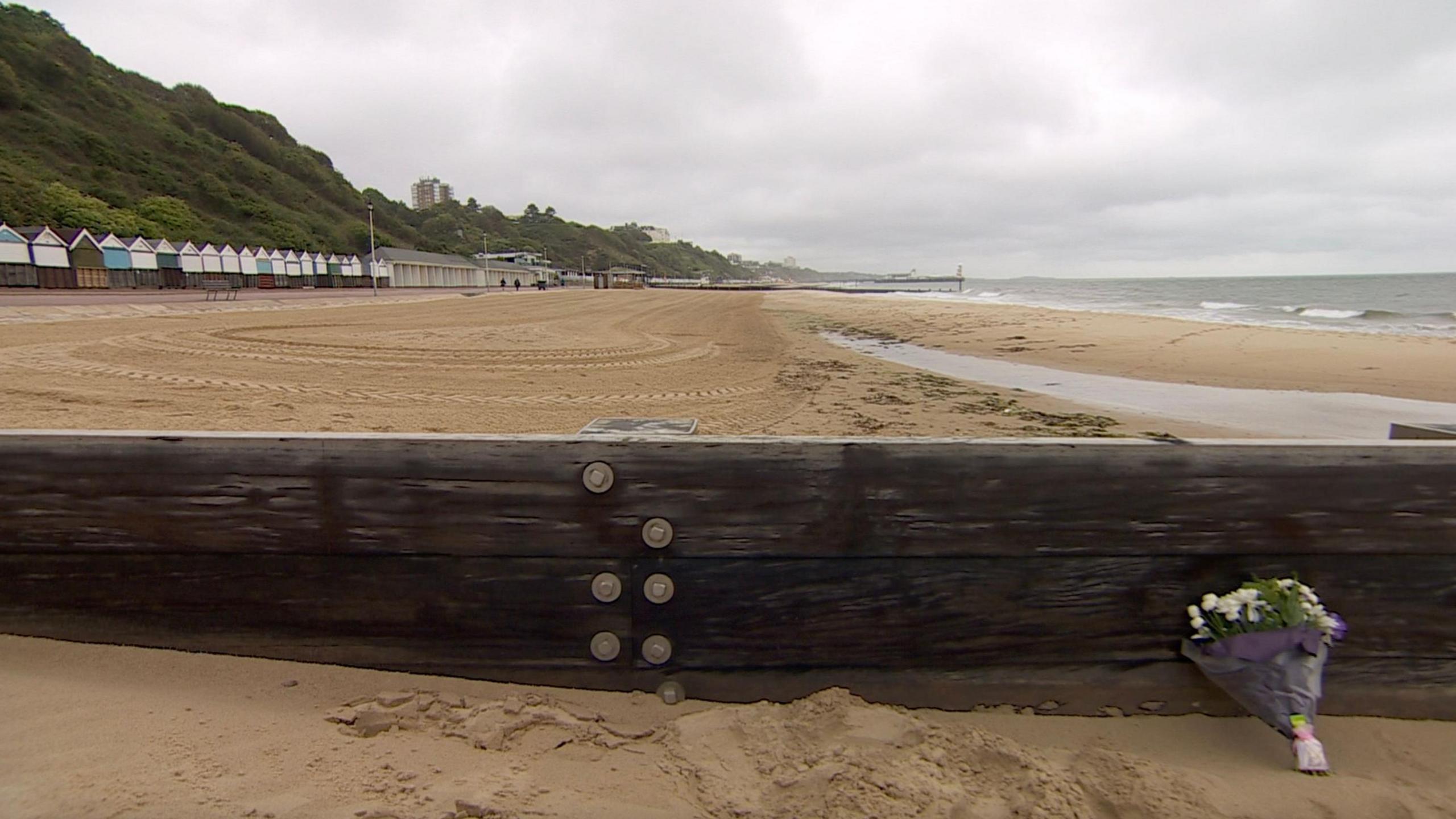 Durley Chine beach with a floral tribute in the foreground and Bournemouth pier in the far distance