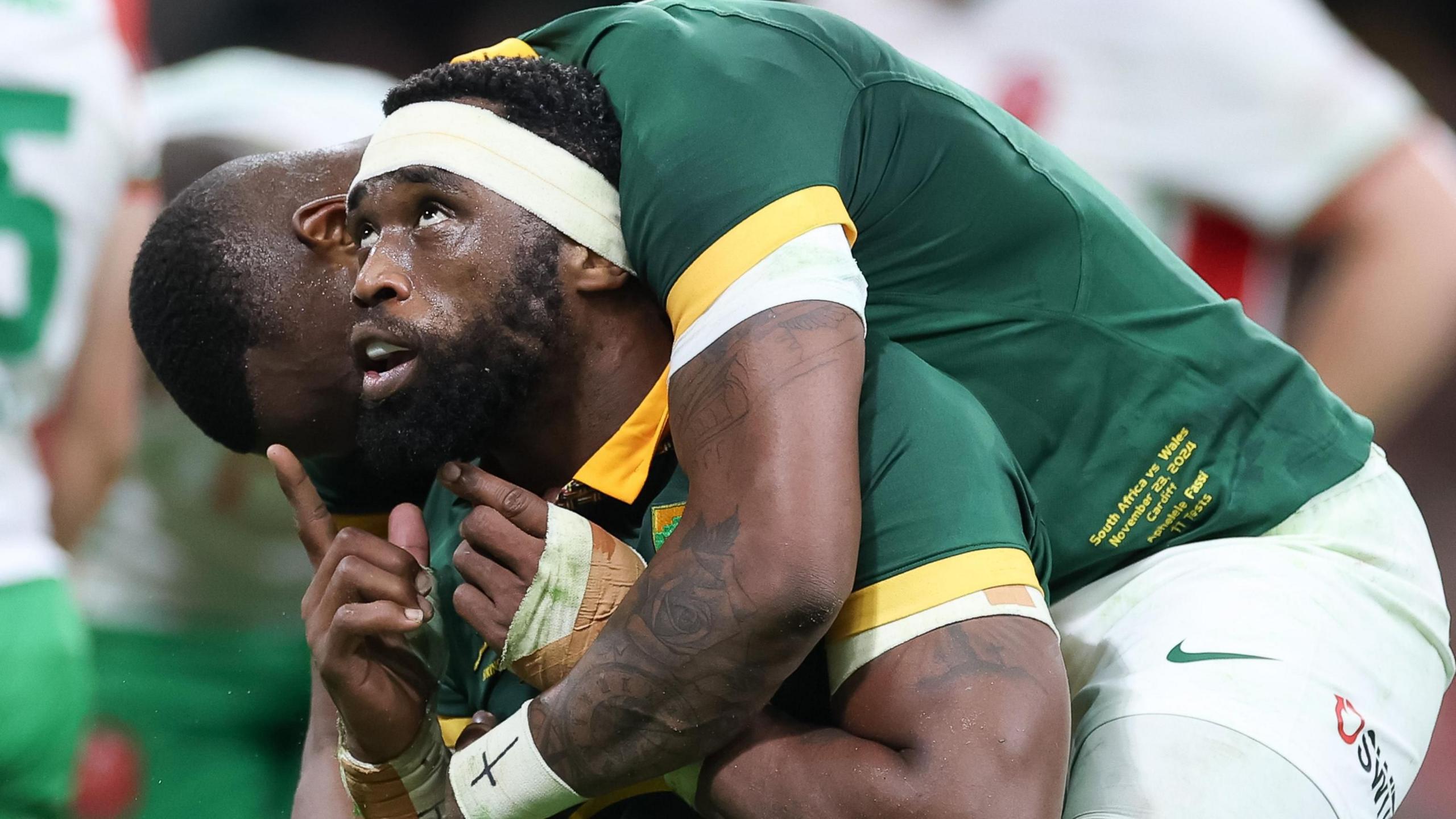 South Africa captain Siya Kolisi looks and points upwards as he is hugged by a team-mate