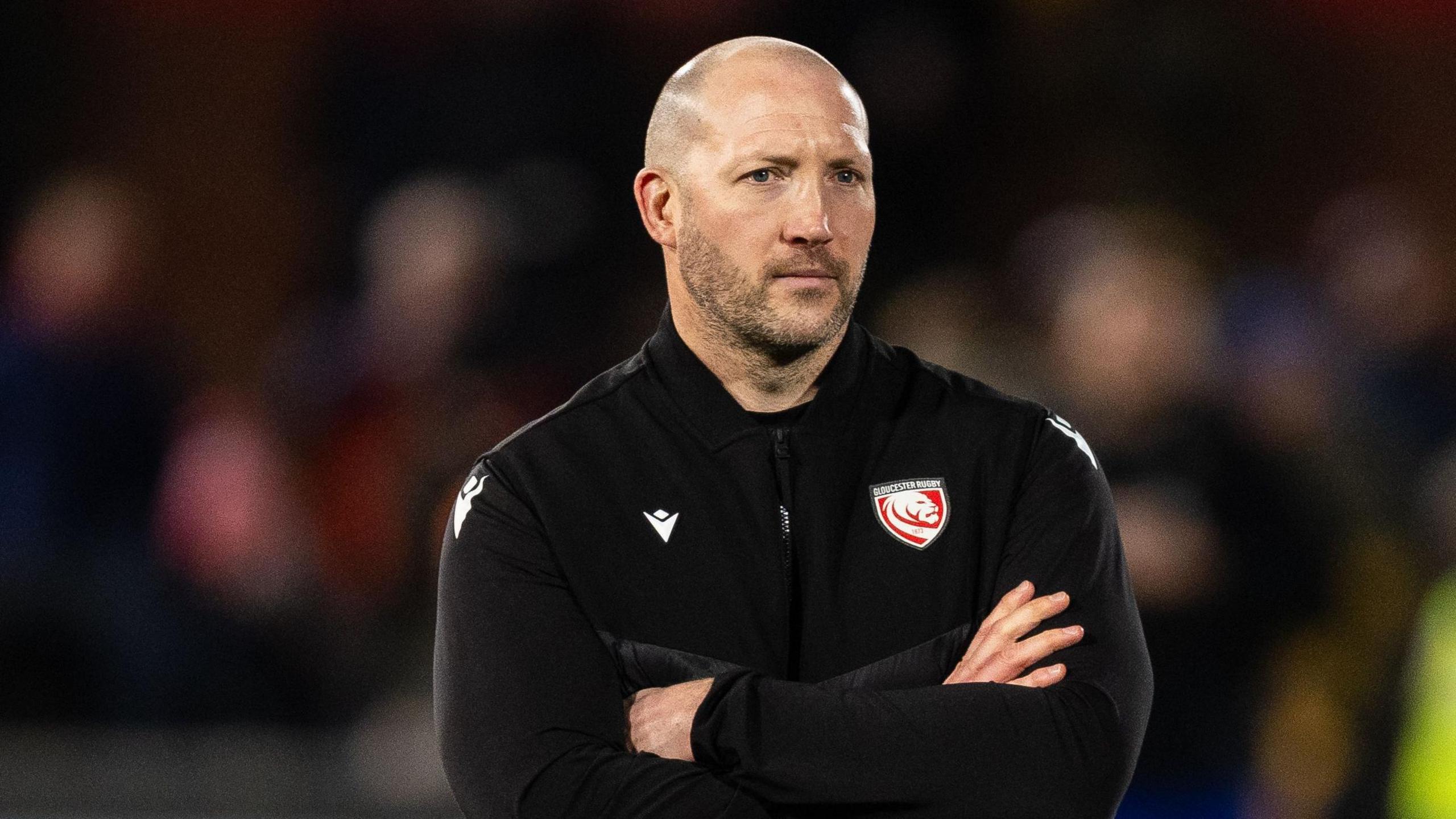 George Skivington stands with his arms folded across his chest