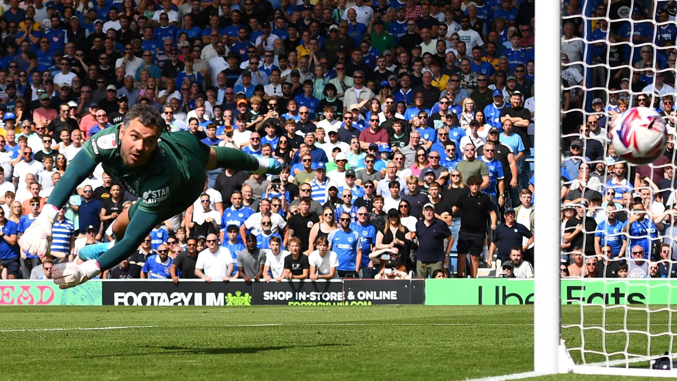 Luton Town goalkeeper John Shea flies to his left attempting a save as the ball goes past him into the net during a match