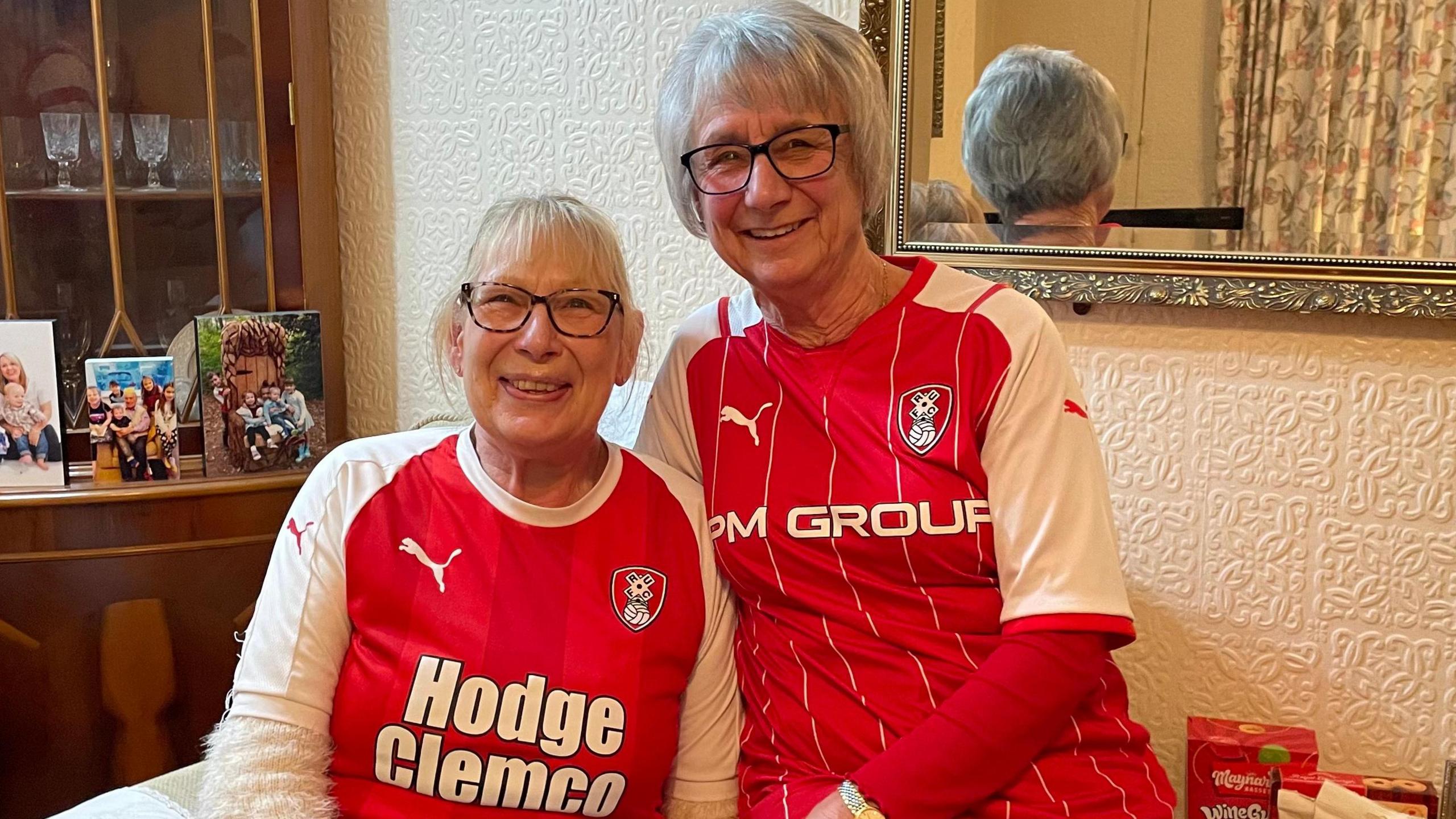 Gillian and Glenys are sat together on an armchair - both in kit.