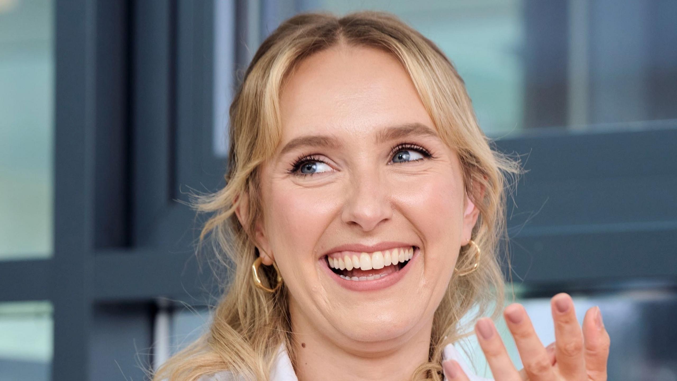 Rose Ayling-Ellis smiles while looking to the side - she has long blonde hair