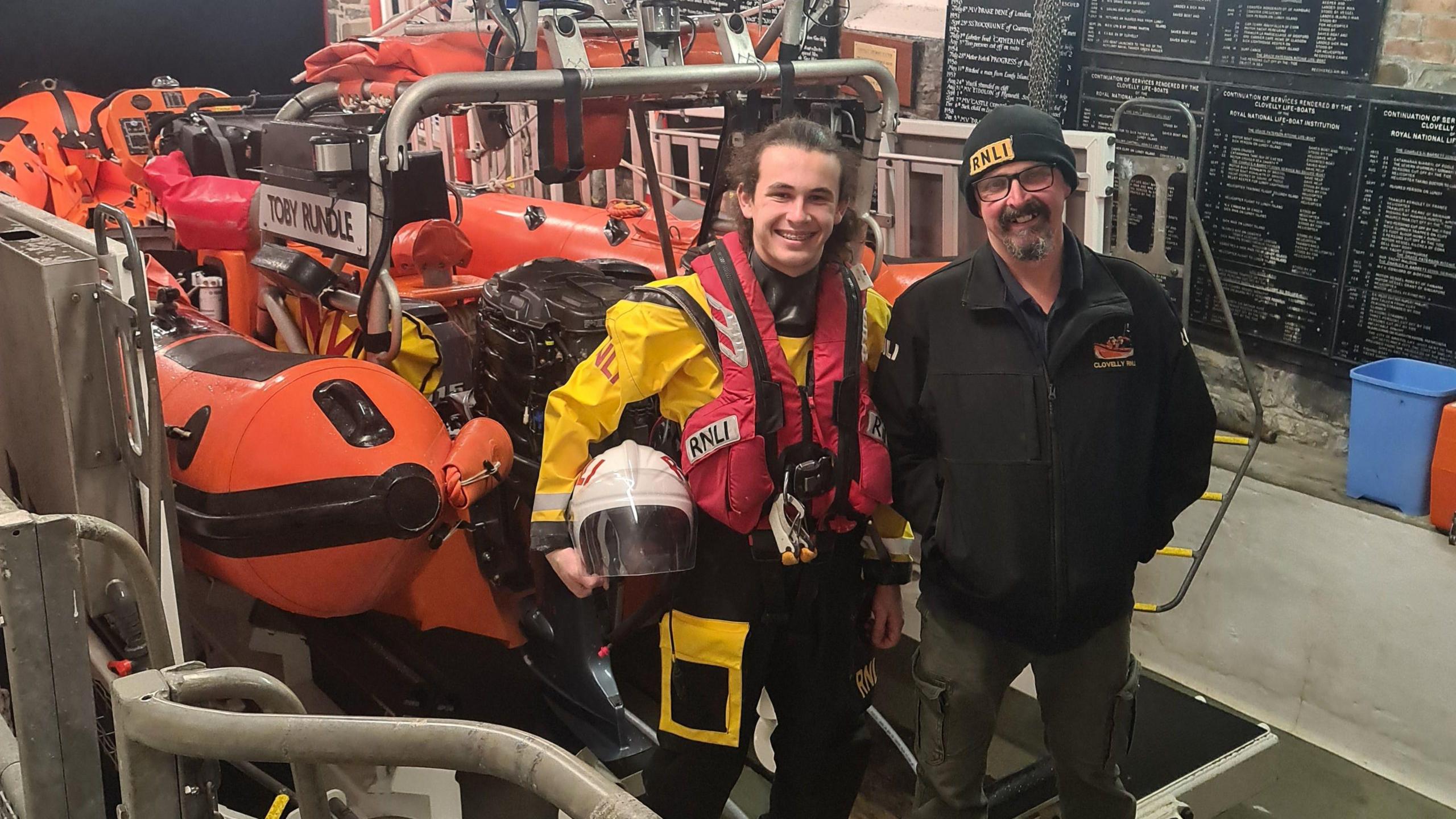 Luca and Larry Sanders standing in front of a rescue boat