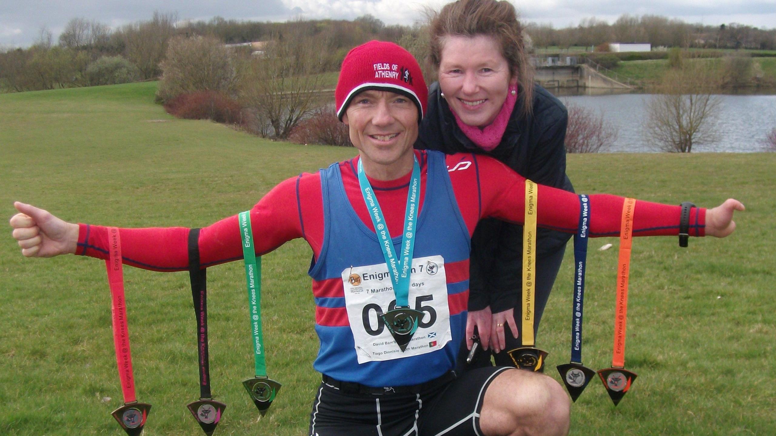 Steve with medals hanging from his arms with his wife Teresa stood behind him