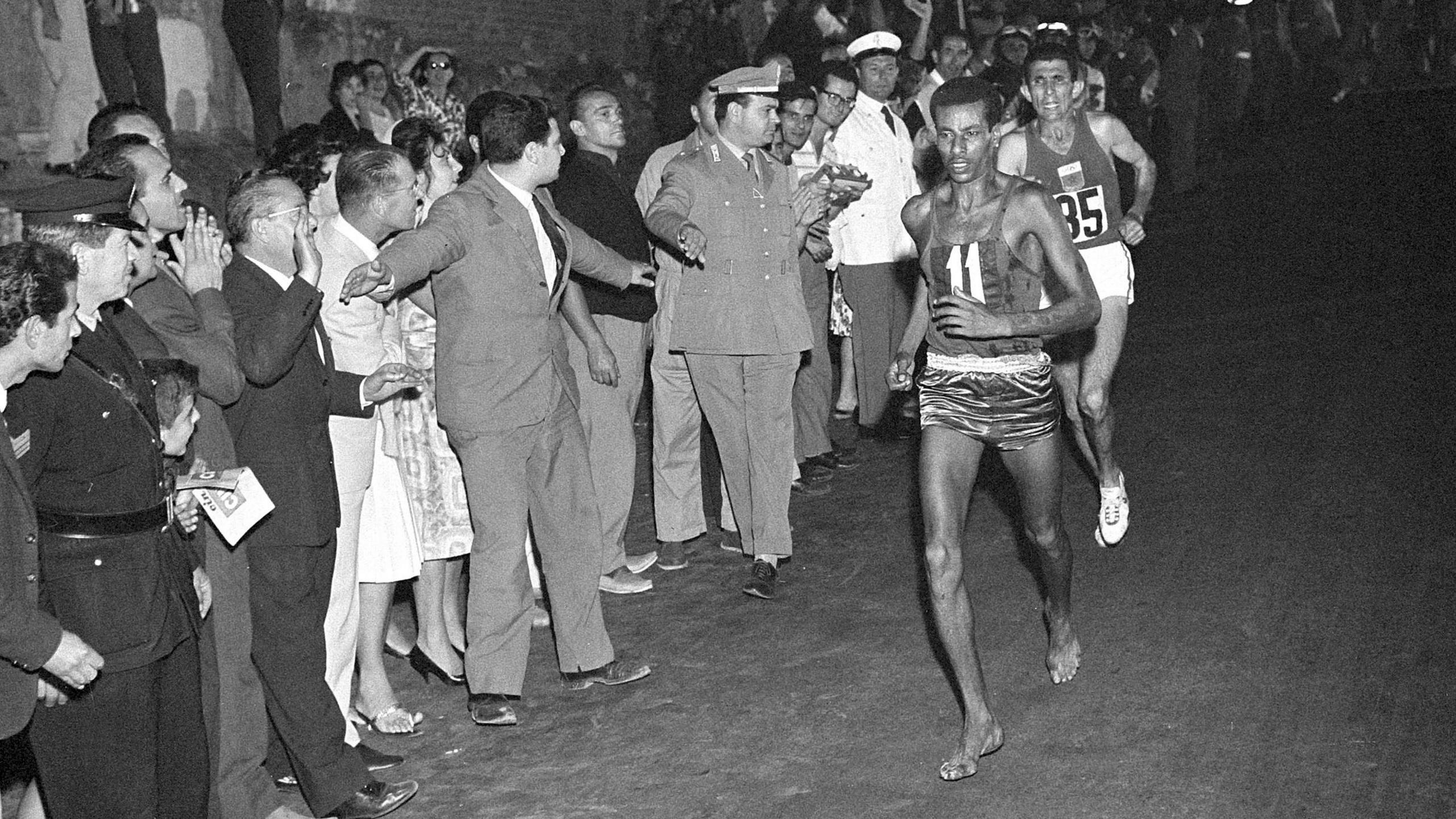 Abebe Bikila running a marathon barefoot as spectators look on