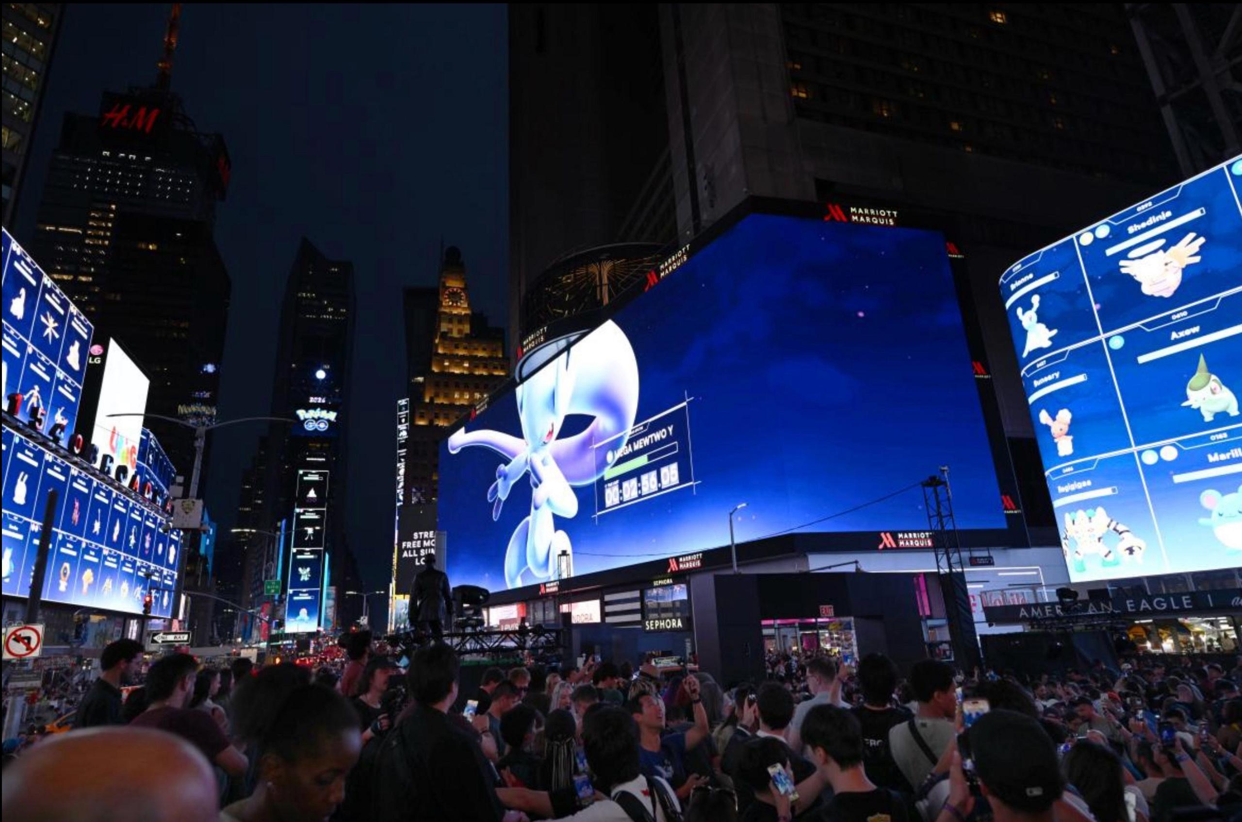Dozens of players gathered in New York City's famous Time Square with pokemon go displayed on several of the big screens. An image of the pokemon Mewtwo is the most prominent. 