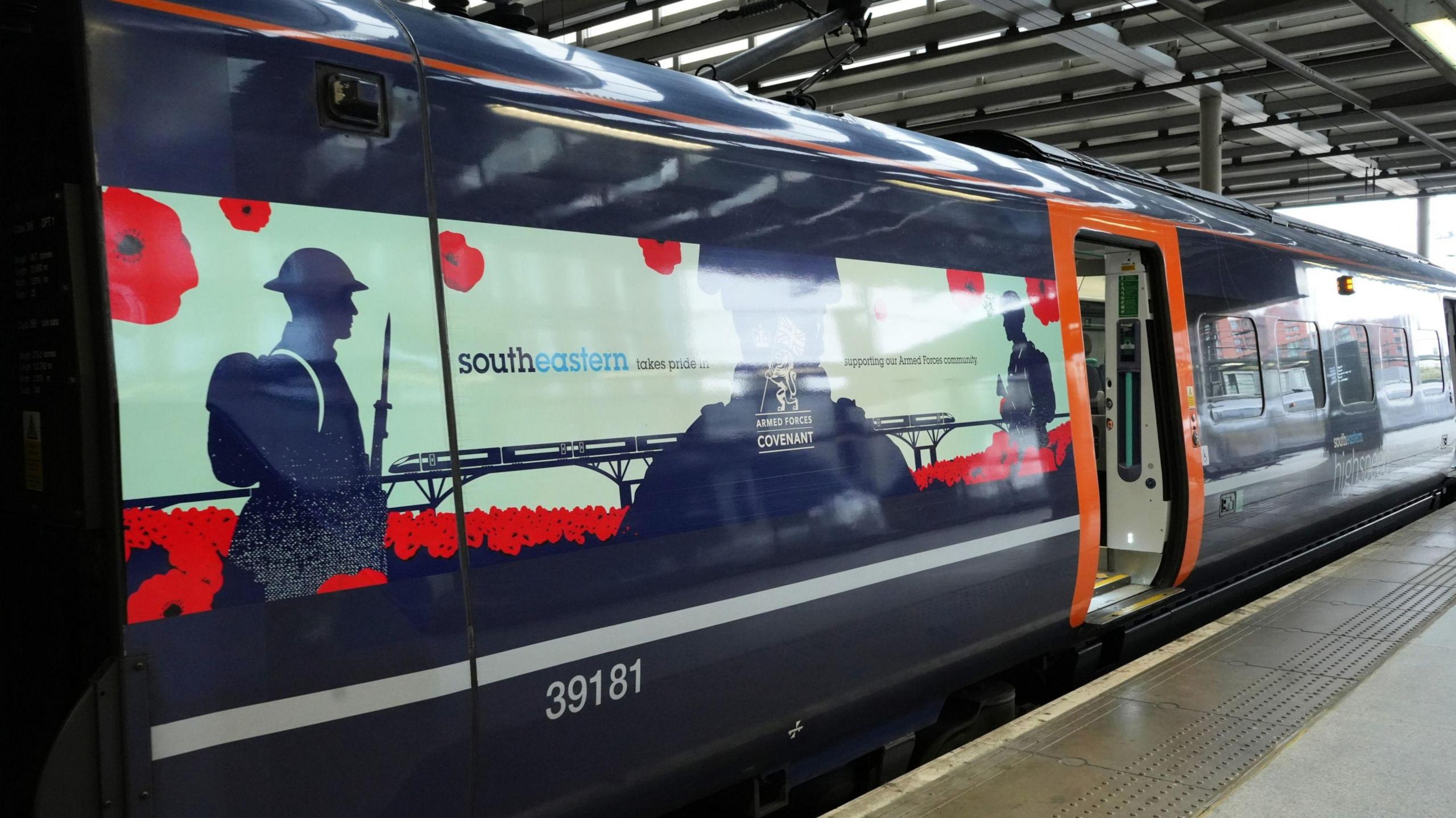 A train decorated with pictures of poppies and silhouettes of soldiers standing at London St Pancras station.