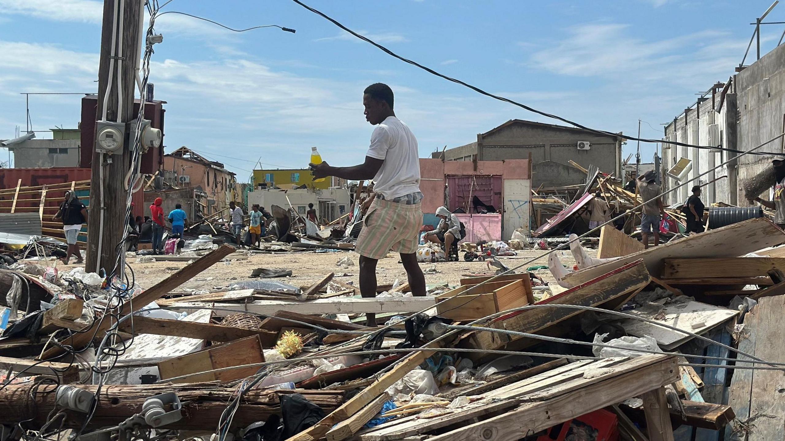 A man is seen looking through debris for food and water