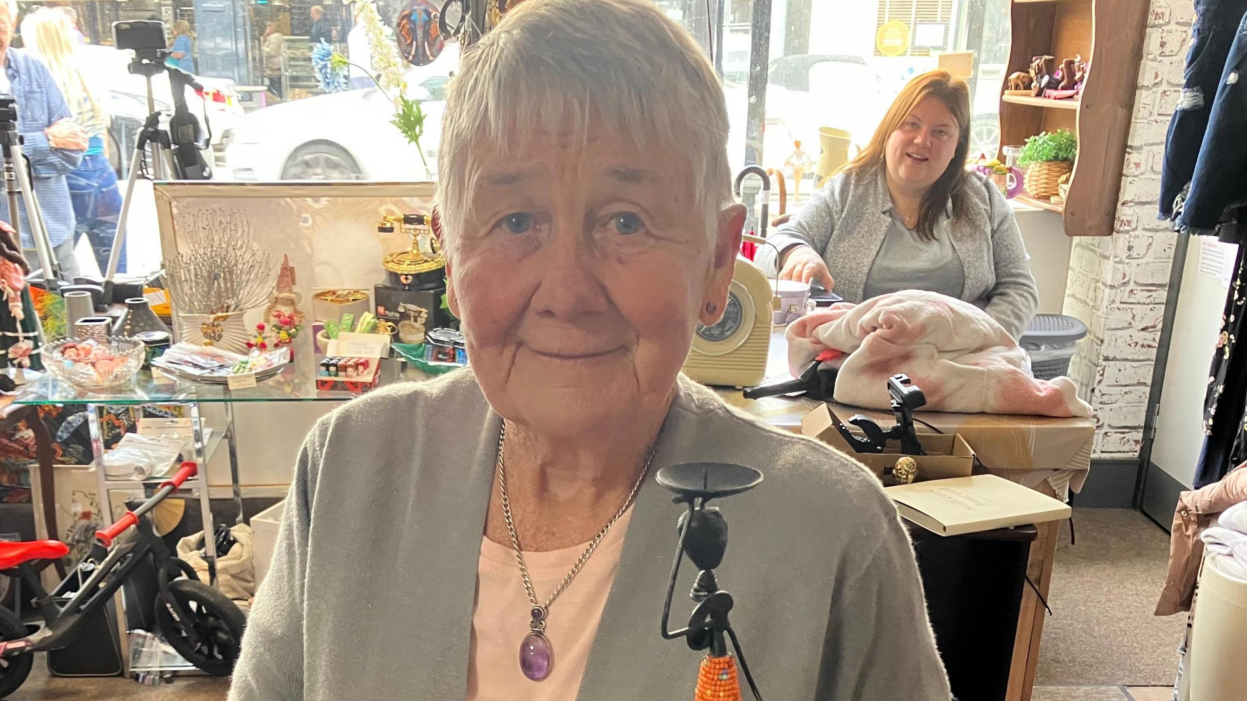 Valerie Walton in Selby charity shop Mama Na Mtoto. 

Valerie Walton is standing in Selby charity shop Mama Na Mtoto she is holding one of the shops African style artefacts.

She is smiling in front of the camera and is wearing a pendant necklace.