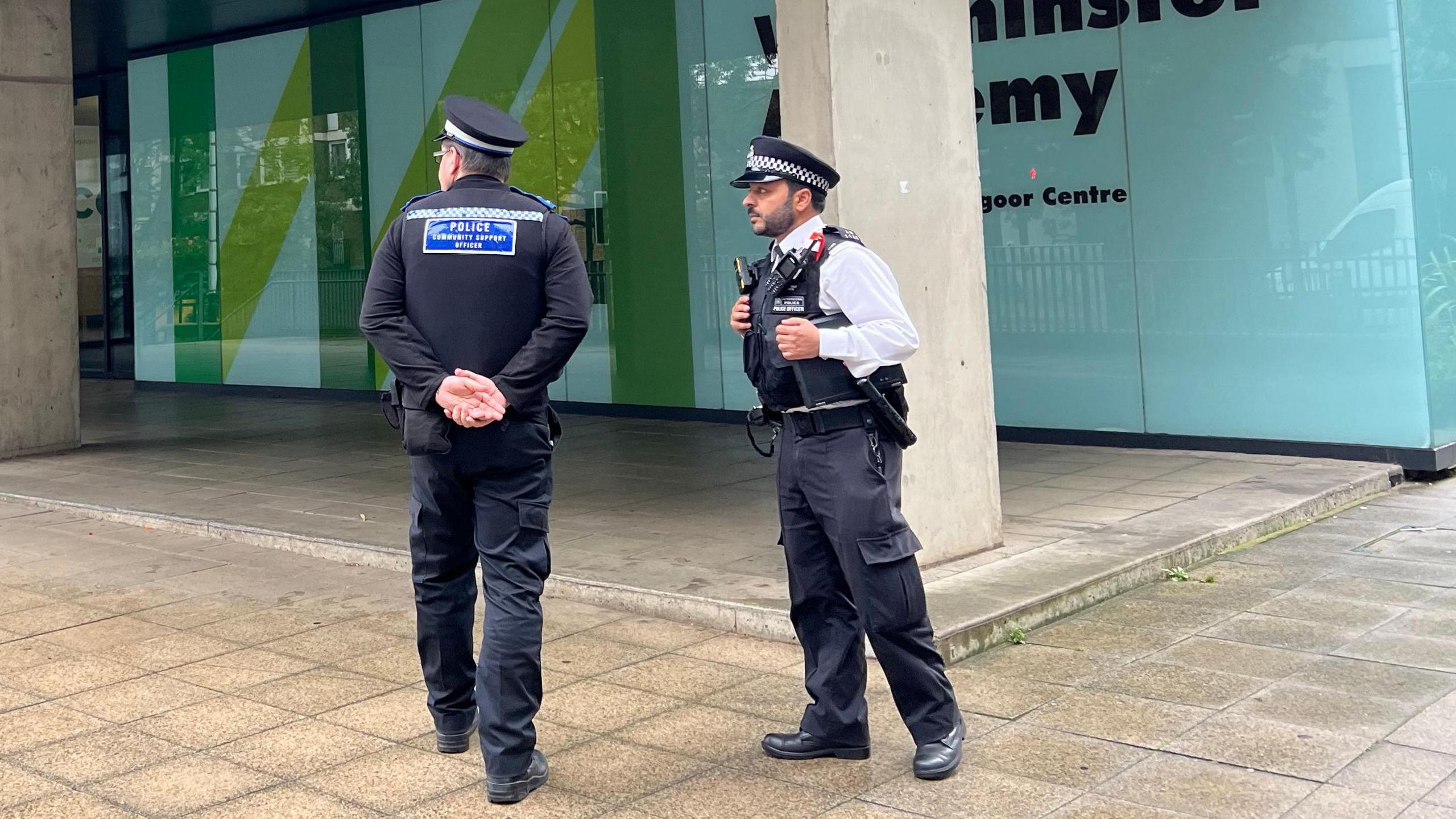 Two police officers standing outside Westminster Academy entrance 