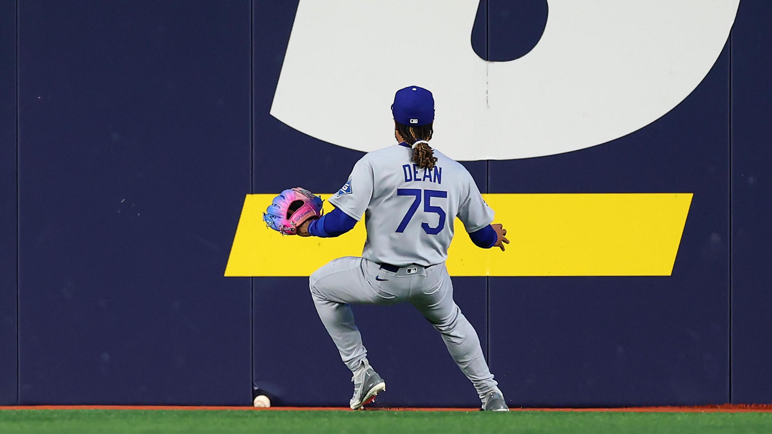 Los Angeles Dodgers centre fielder Justin Dean runs towards the wall as the ball wedges underneath