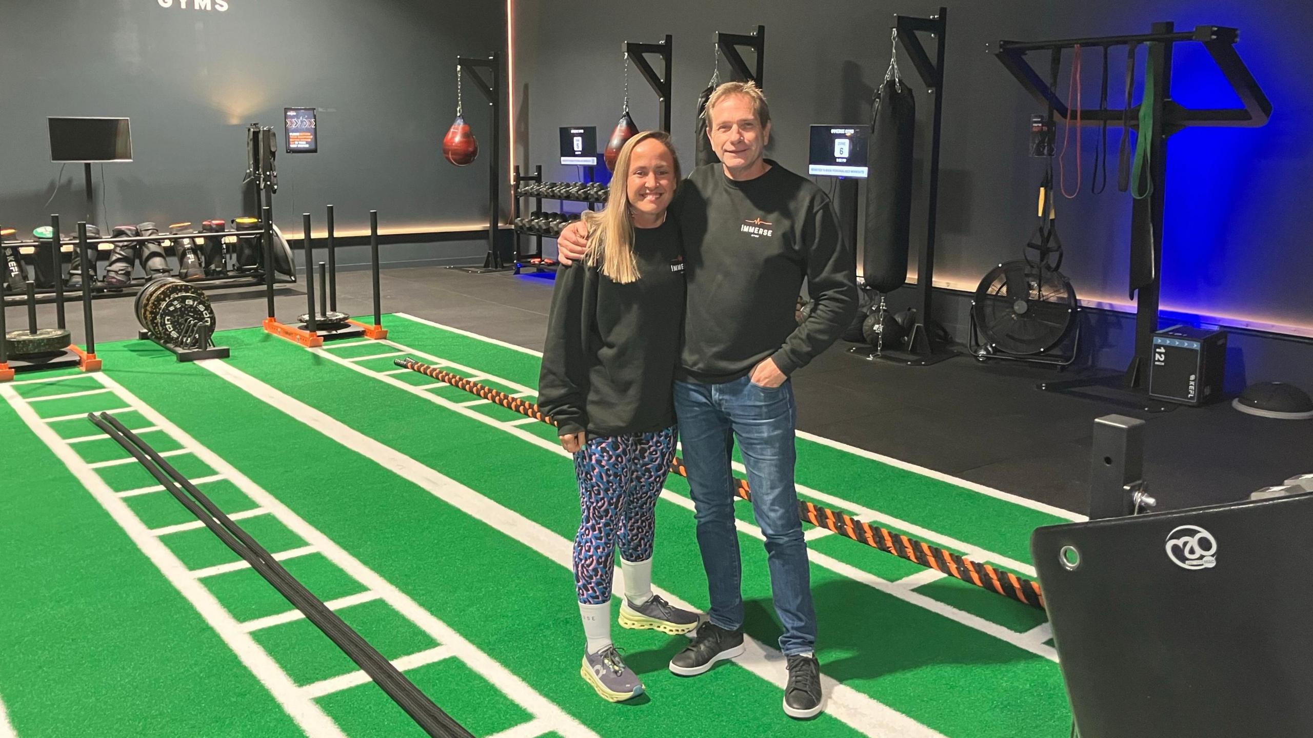 Sophia Guiqui and Terry Mohr (right hand side) inside their gym surrounded by equipment