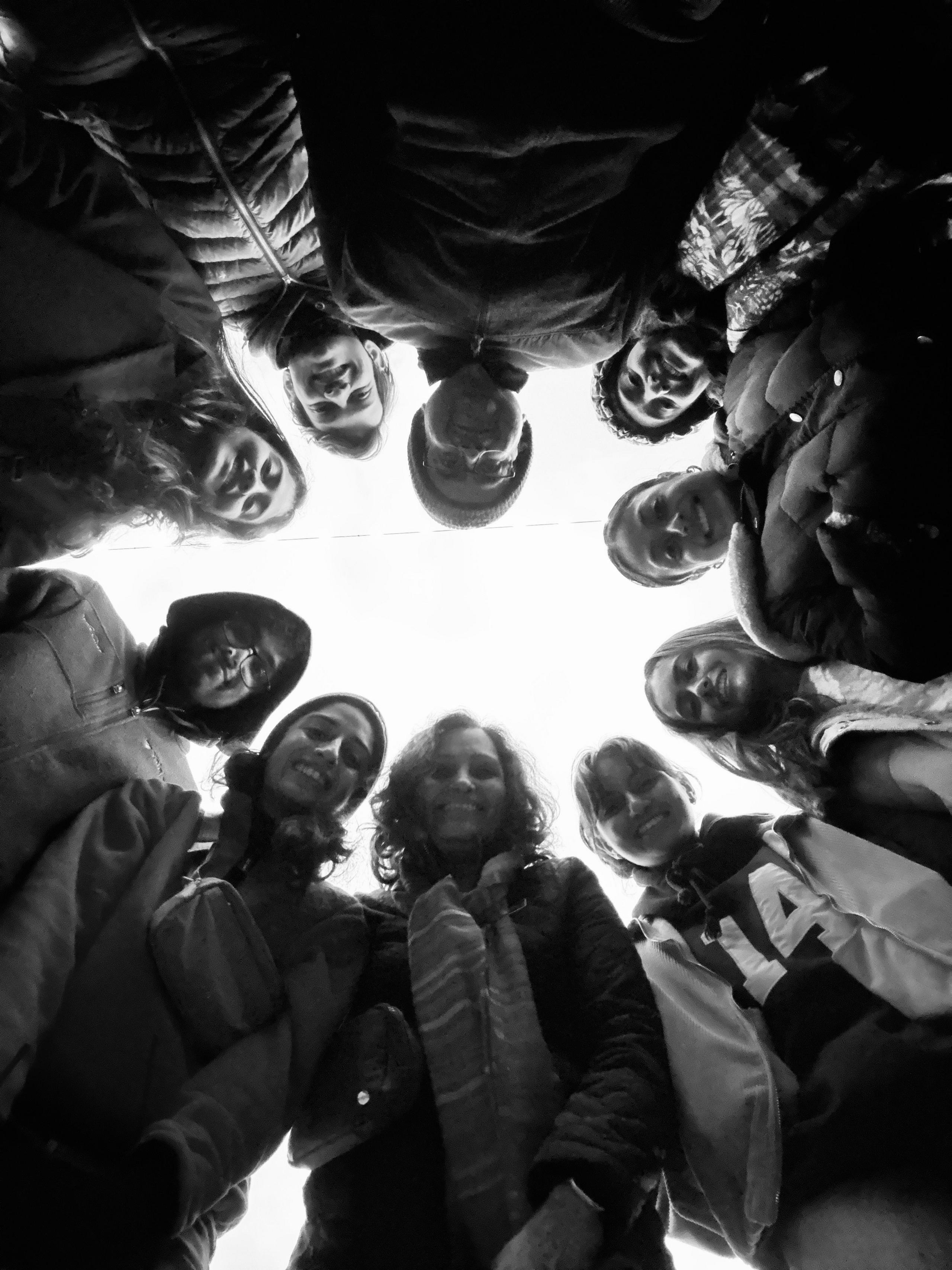 People lean in together in circle, looking down on the camera