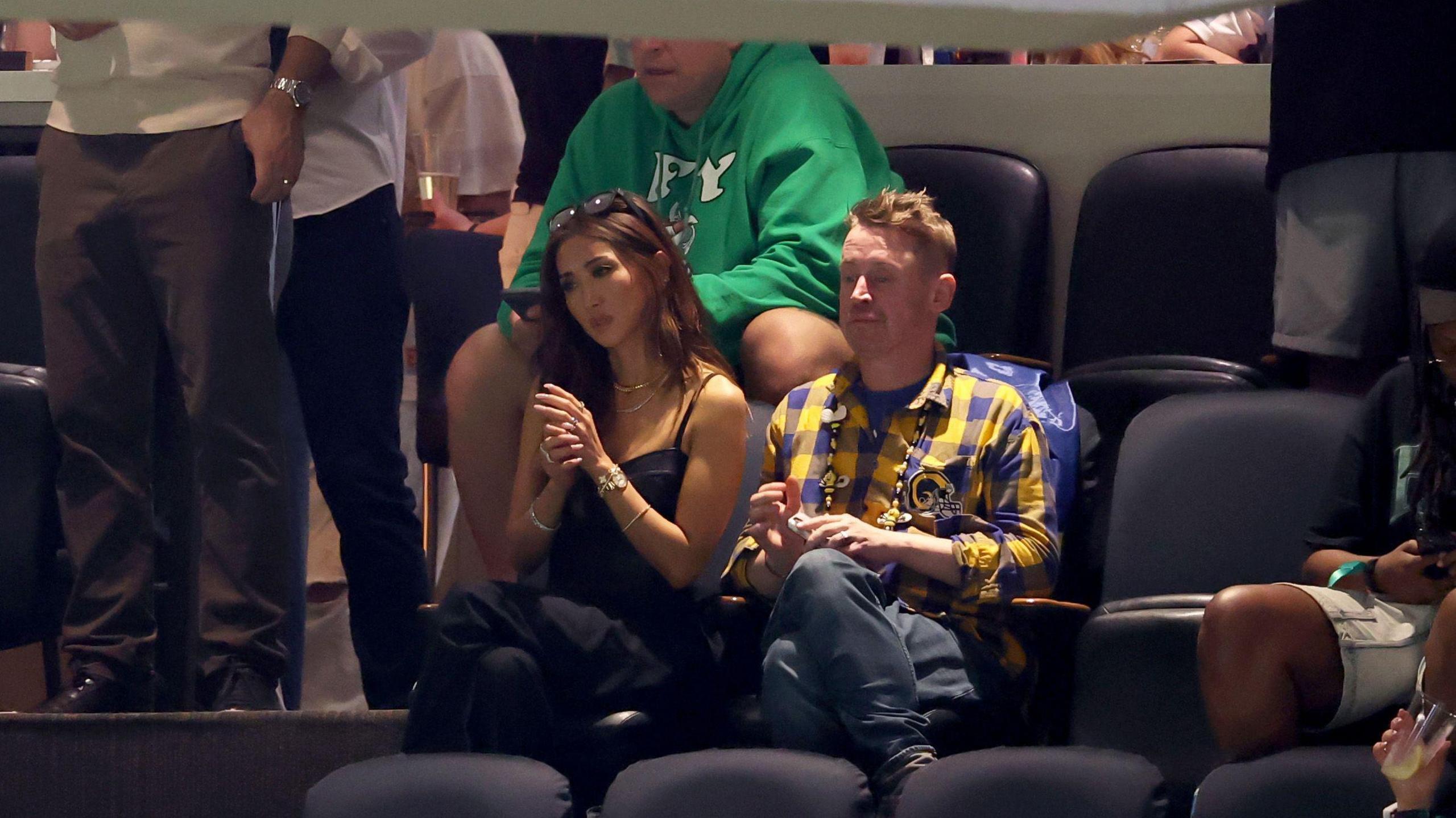 Brenda Song and Macaulay Culkin sit next to one another