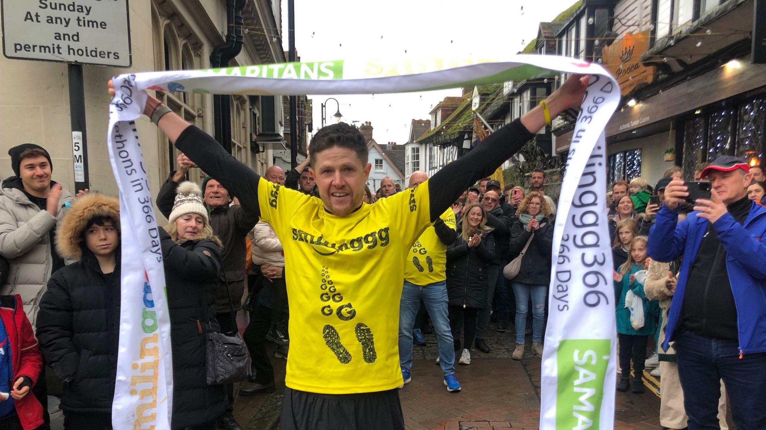 A man holds a banner after completing a race. 