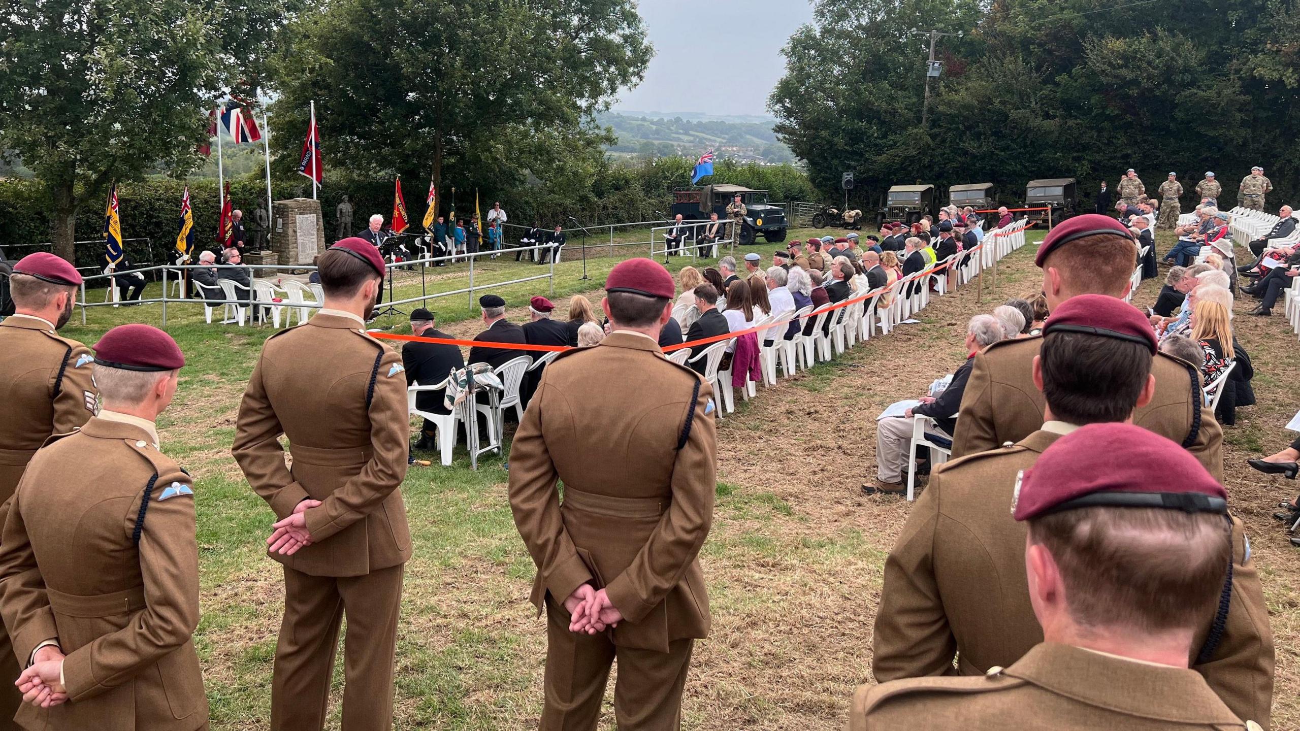 Serving service personnel standing to the left of the gathering for the memorial.