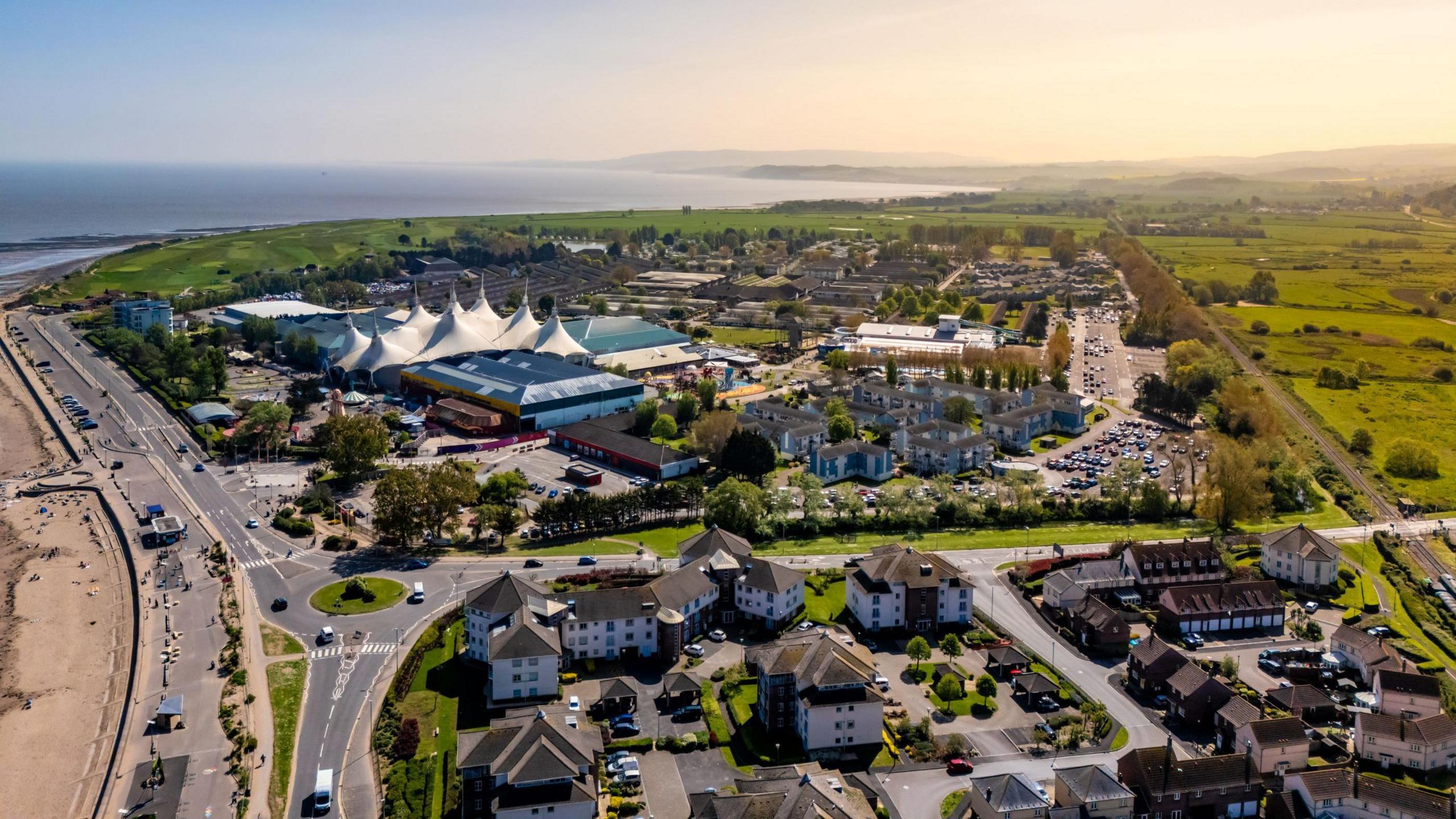 An aerial shot of Minehead in Somerset. It is a sunny day and the distinctive white tent-like structure of Butlins is visible as well as the coastline in the distance