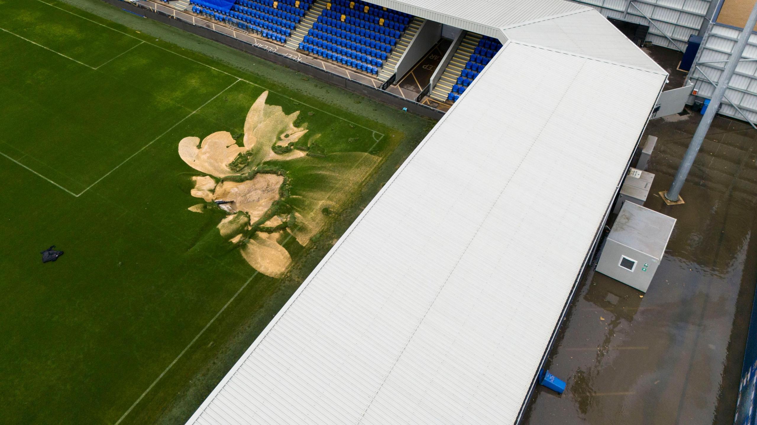 An aerial shot showing damage to the pitch and standing water on the concourse at Plough Lane