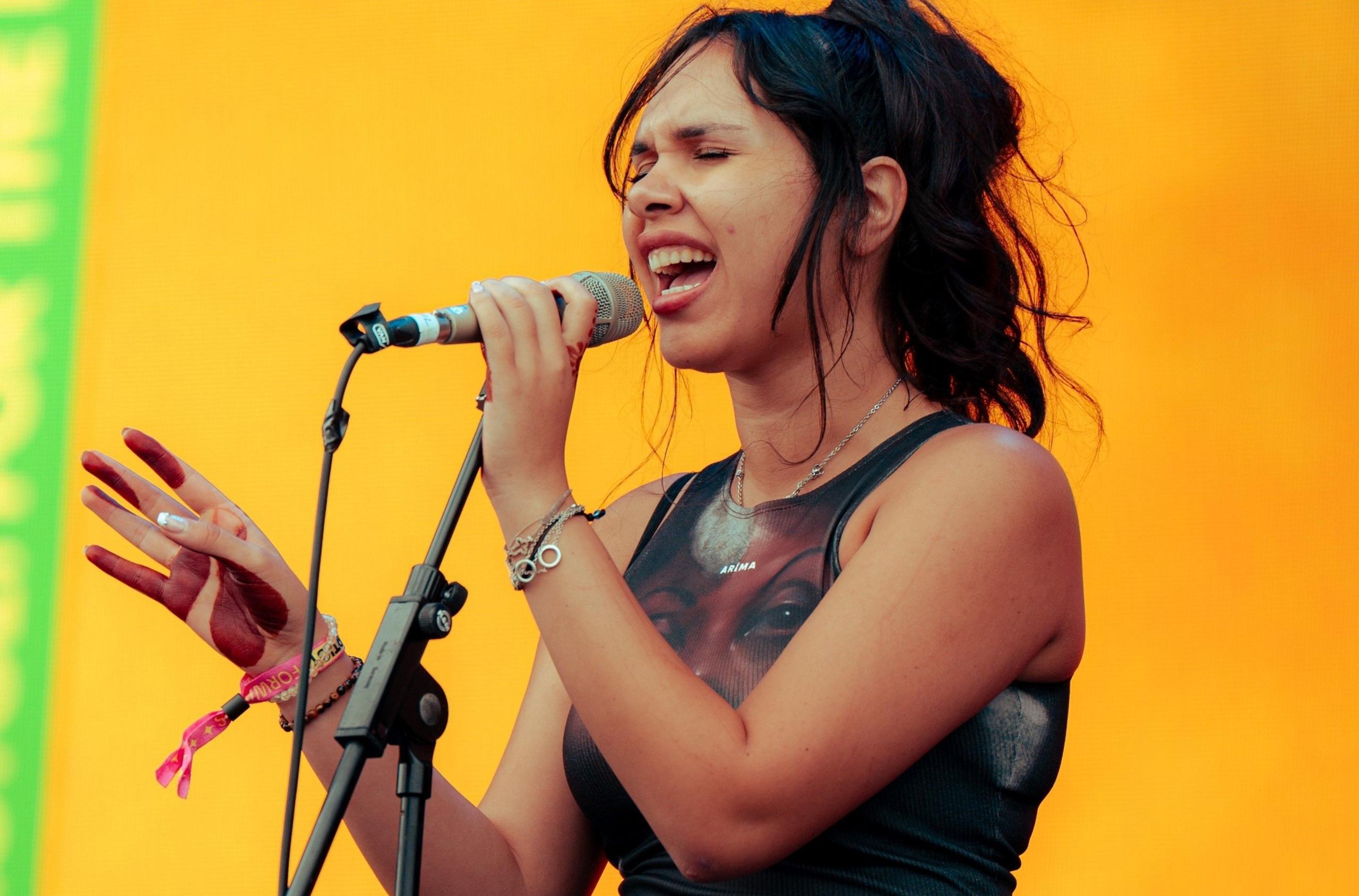 A woman sings at Forwards Festival in Bristol. She has dark hair and a dark vest top