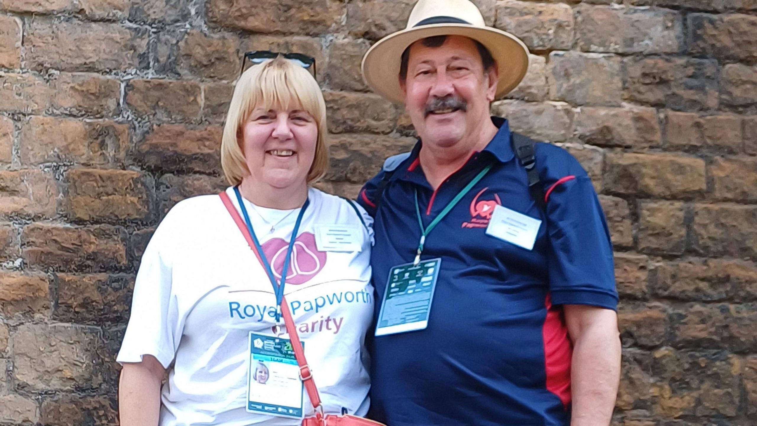 Mr and Mrs Canning stood together smiling in front of a brick wall.