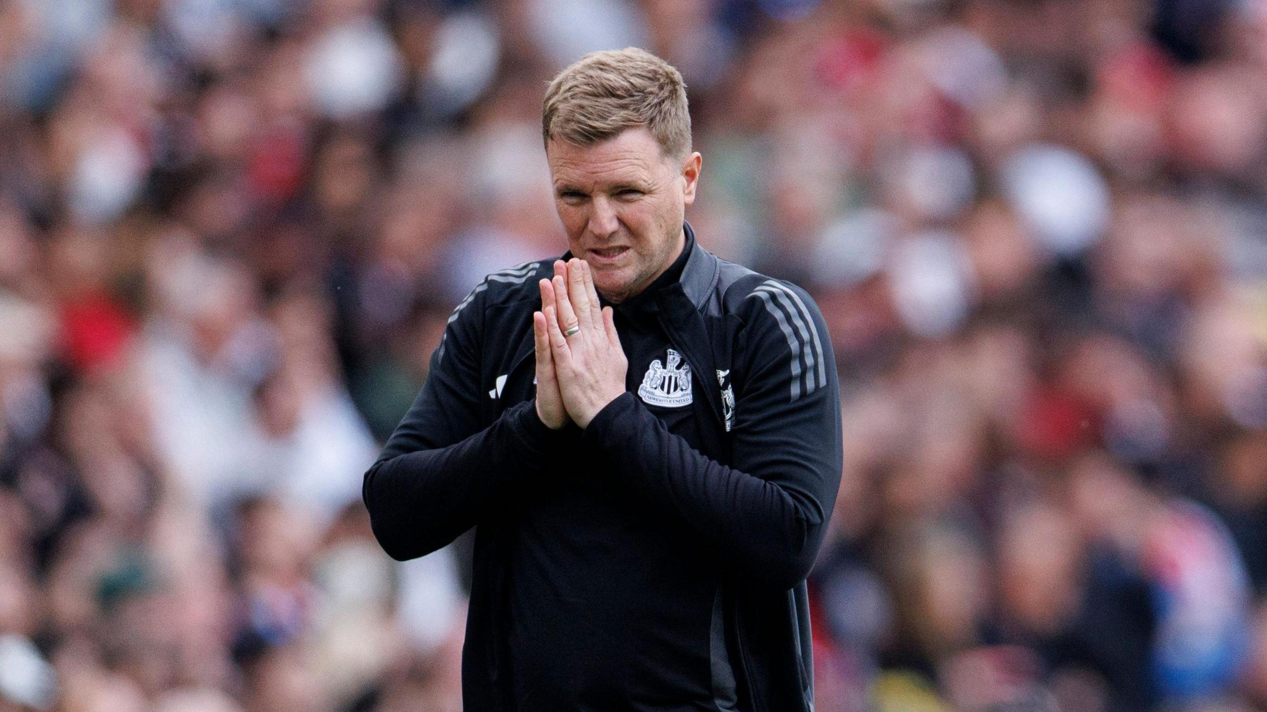Eddie Howe stands with his hands together in a prayer-like pose