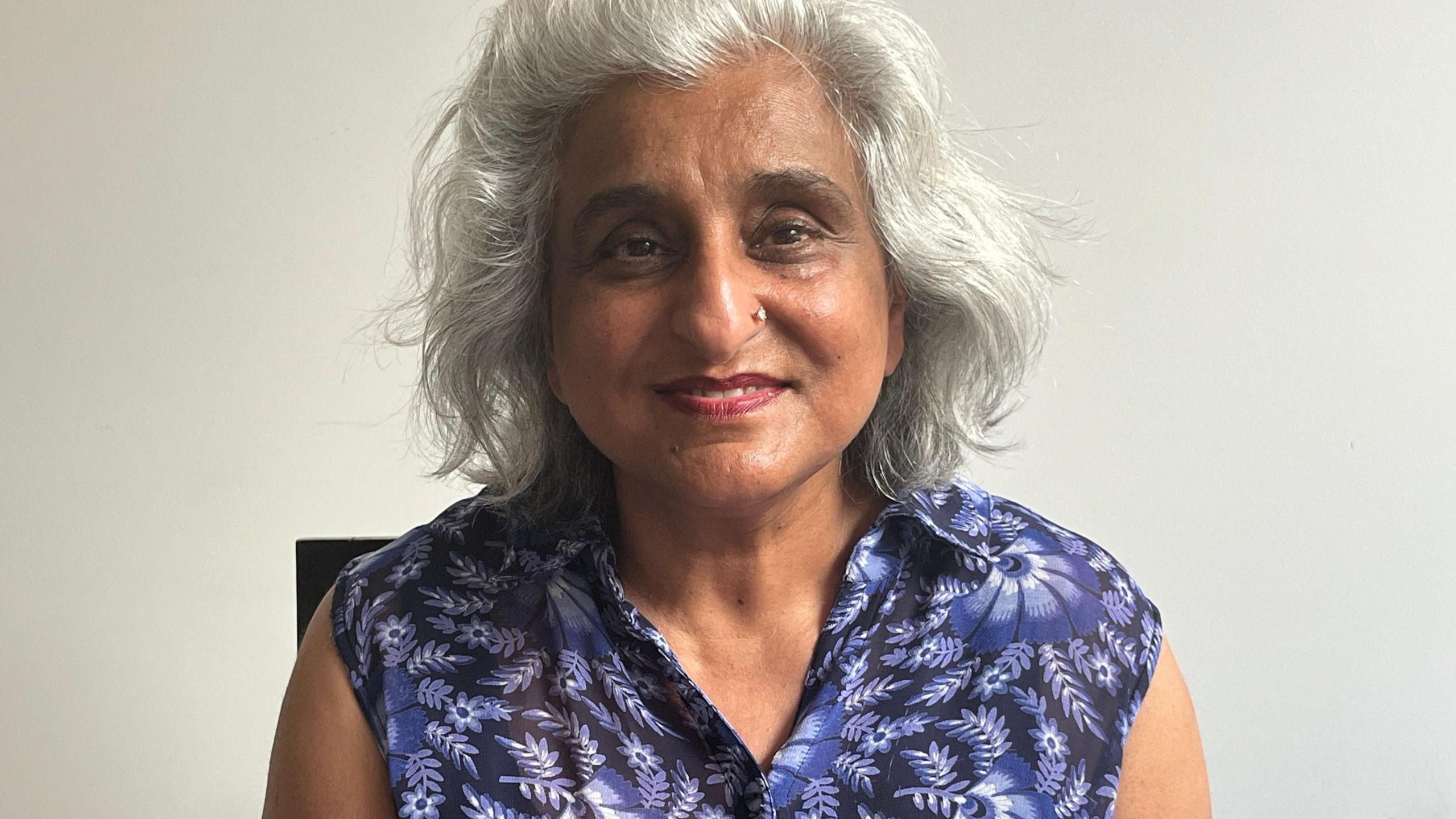 Neelam Devesher, smiles at the camera, with a purple blouse on