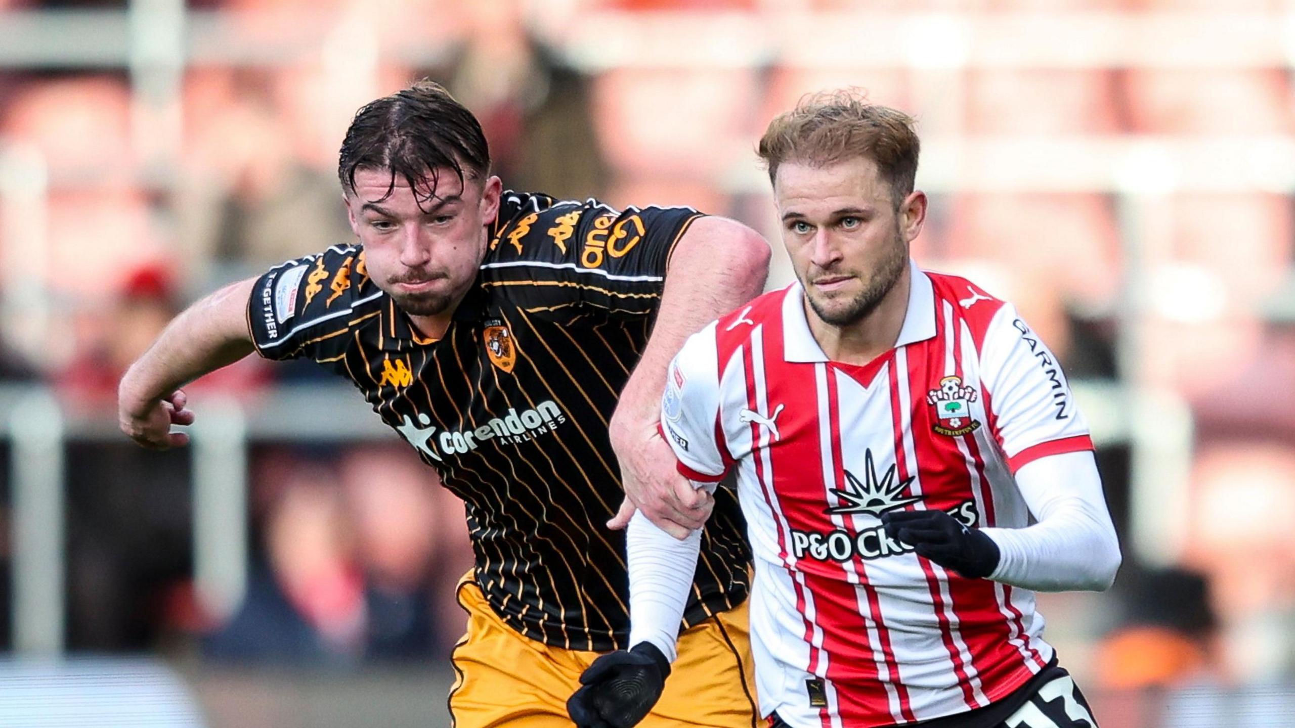 Hull defender Charlie Hughes has his left hand on the right shoulder of Southampton player Leo Scienza, who is wearing gloves 
