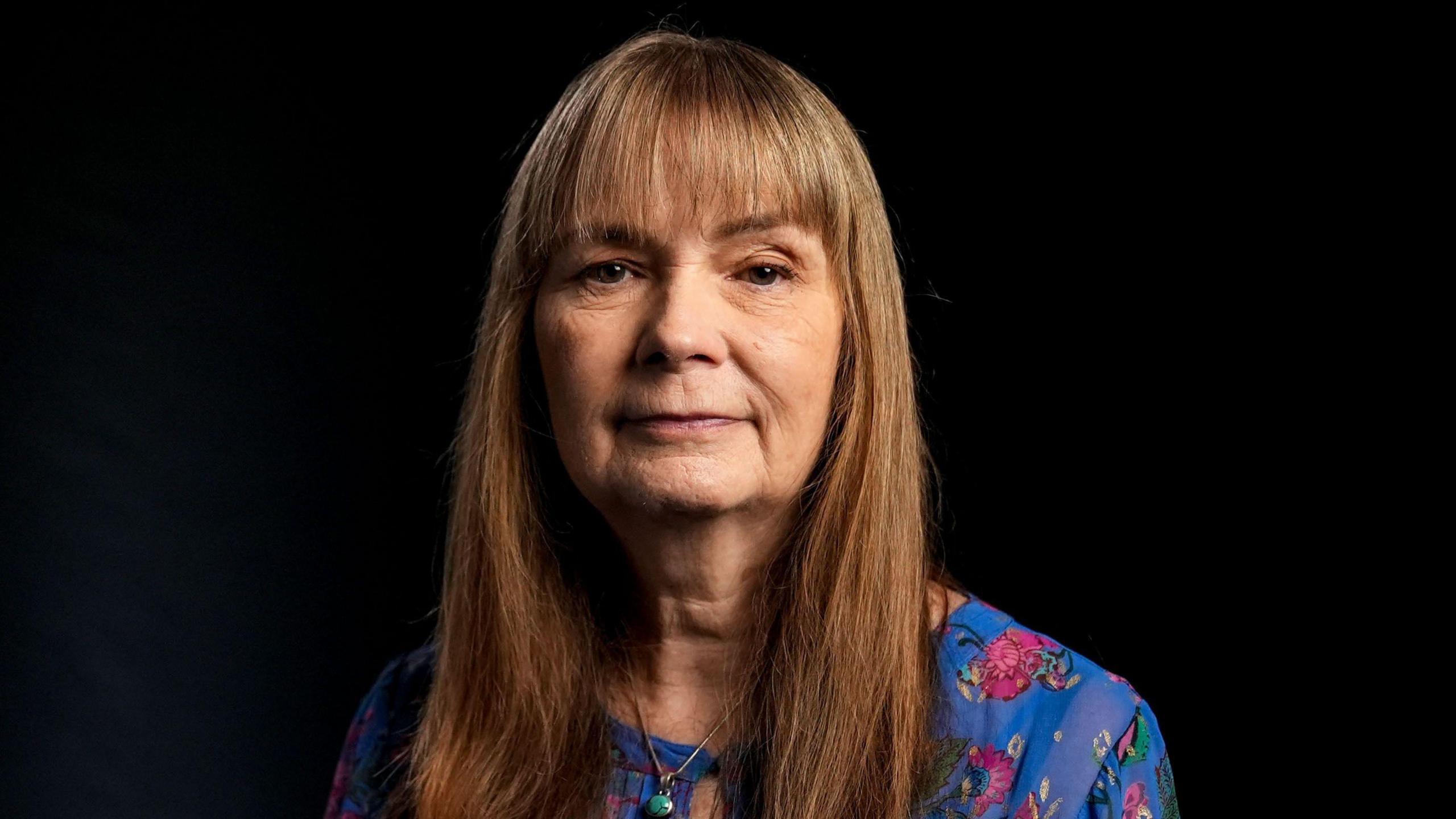 A woman with long brown hair and a straight fringe. 