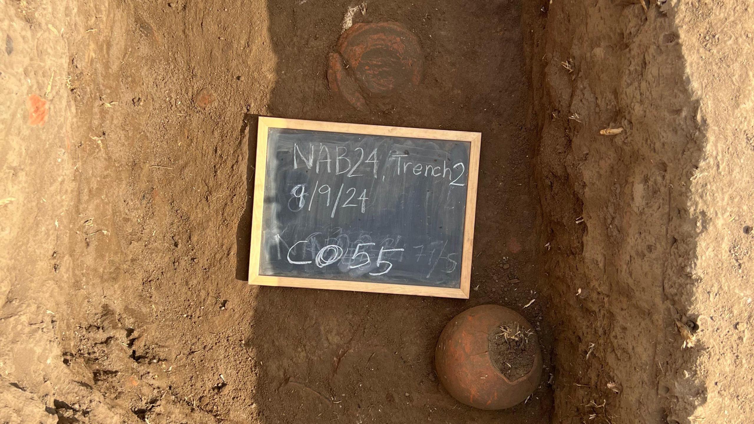Two bowls can be seen in a trench, with a sign saying trench two and with the date 9 September 2024.