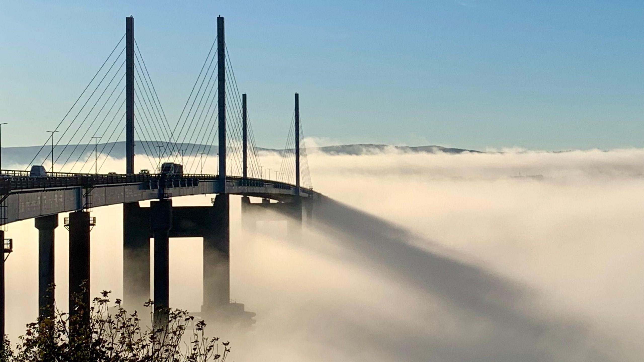 A bridge emerging from the mist while casting long shadows