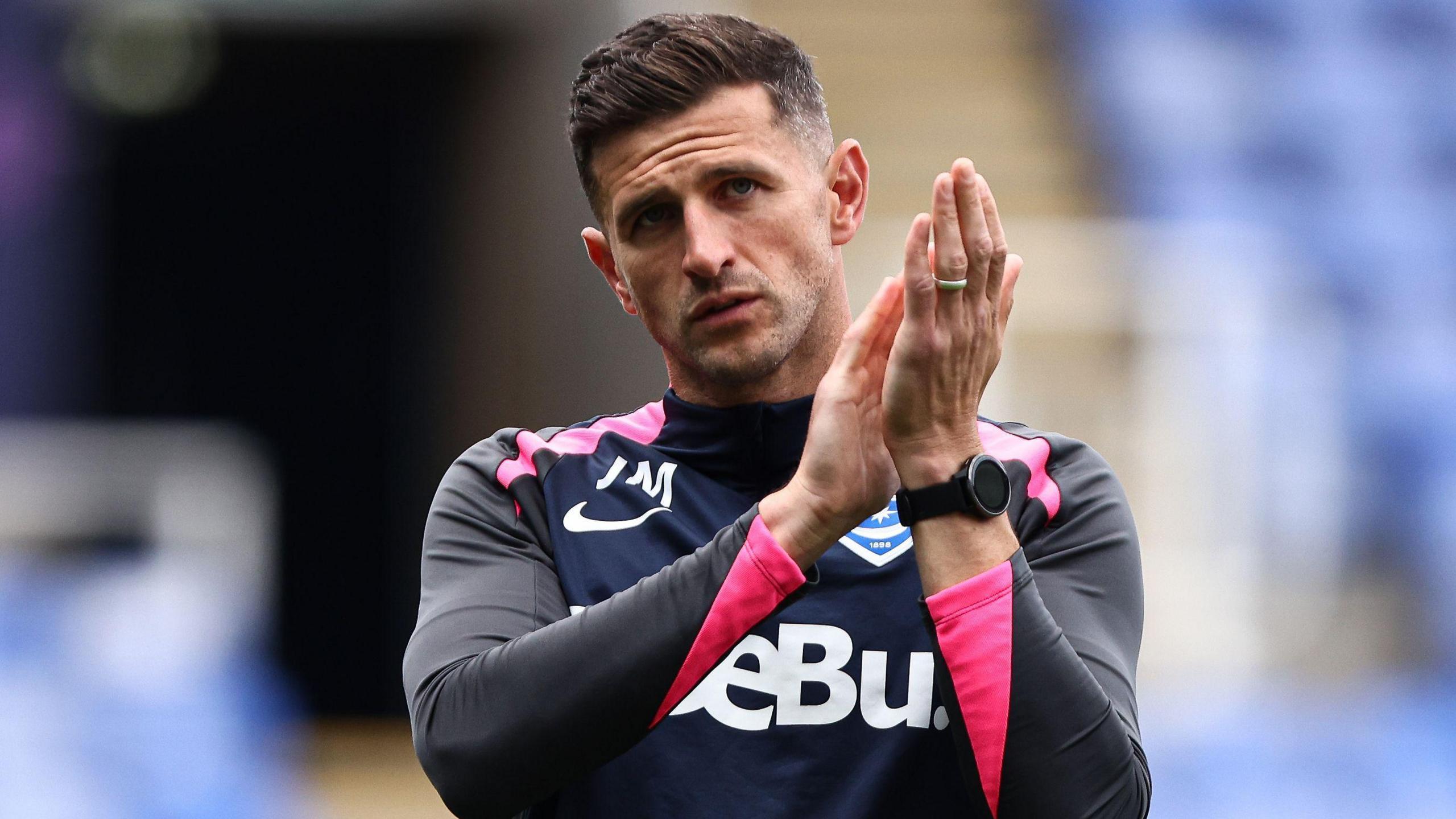 John Mousinho applauds the fans after a game.