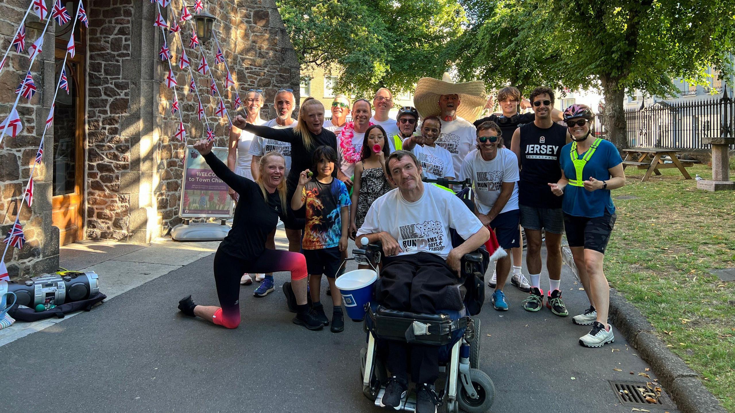 A group of runners waves at the camera next to a church