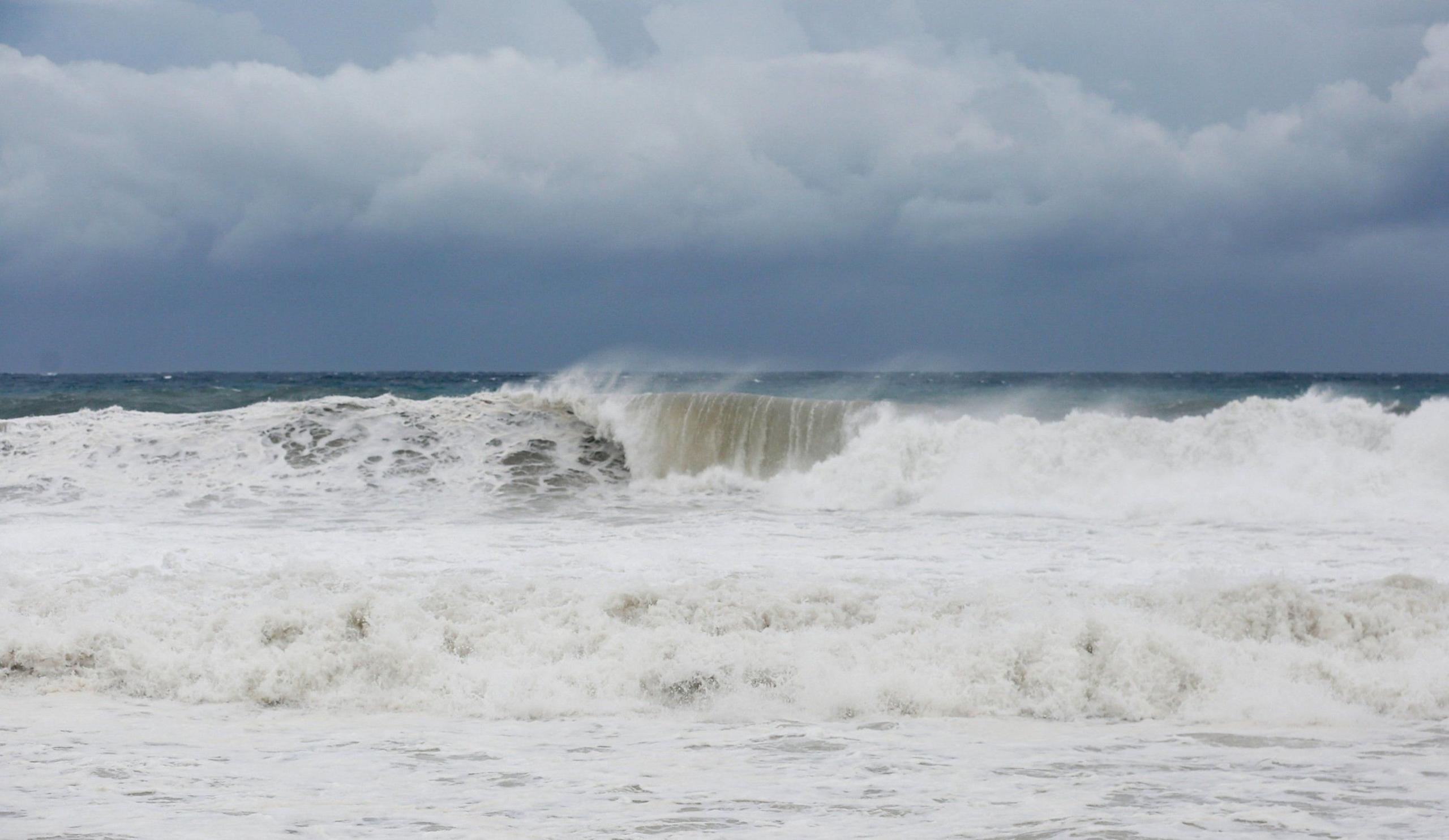 Waves crash on the beach, mainly white water under a deep grey-blue sky as Hurricane Melissa approaches Port Royal, Jamaica,